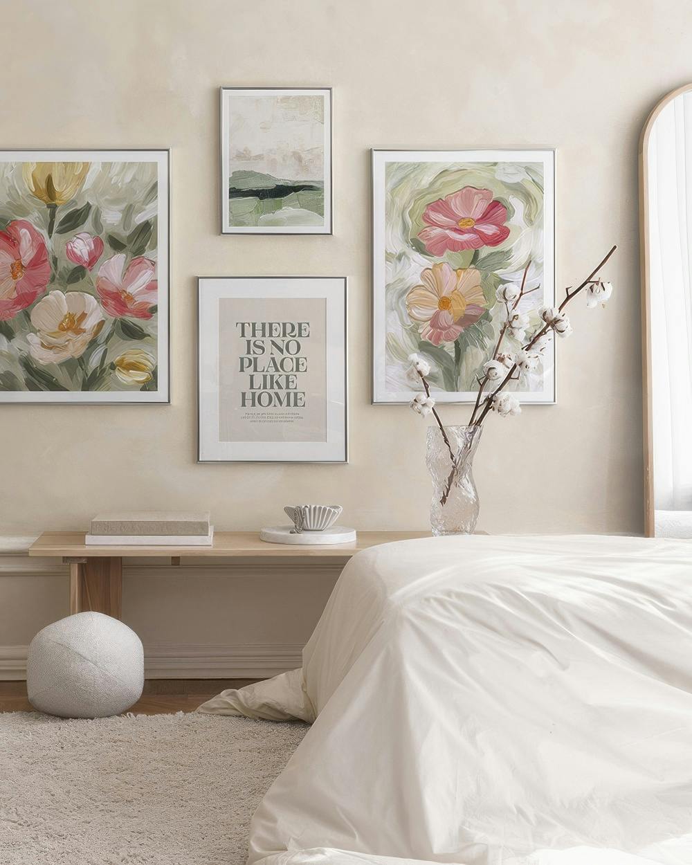 En bildevegg med fire malerier: abstrakte blomster i rosa, gul og grønn, et landskap i grønn og beige, og tekstplakaten There is