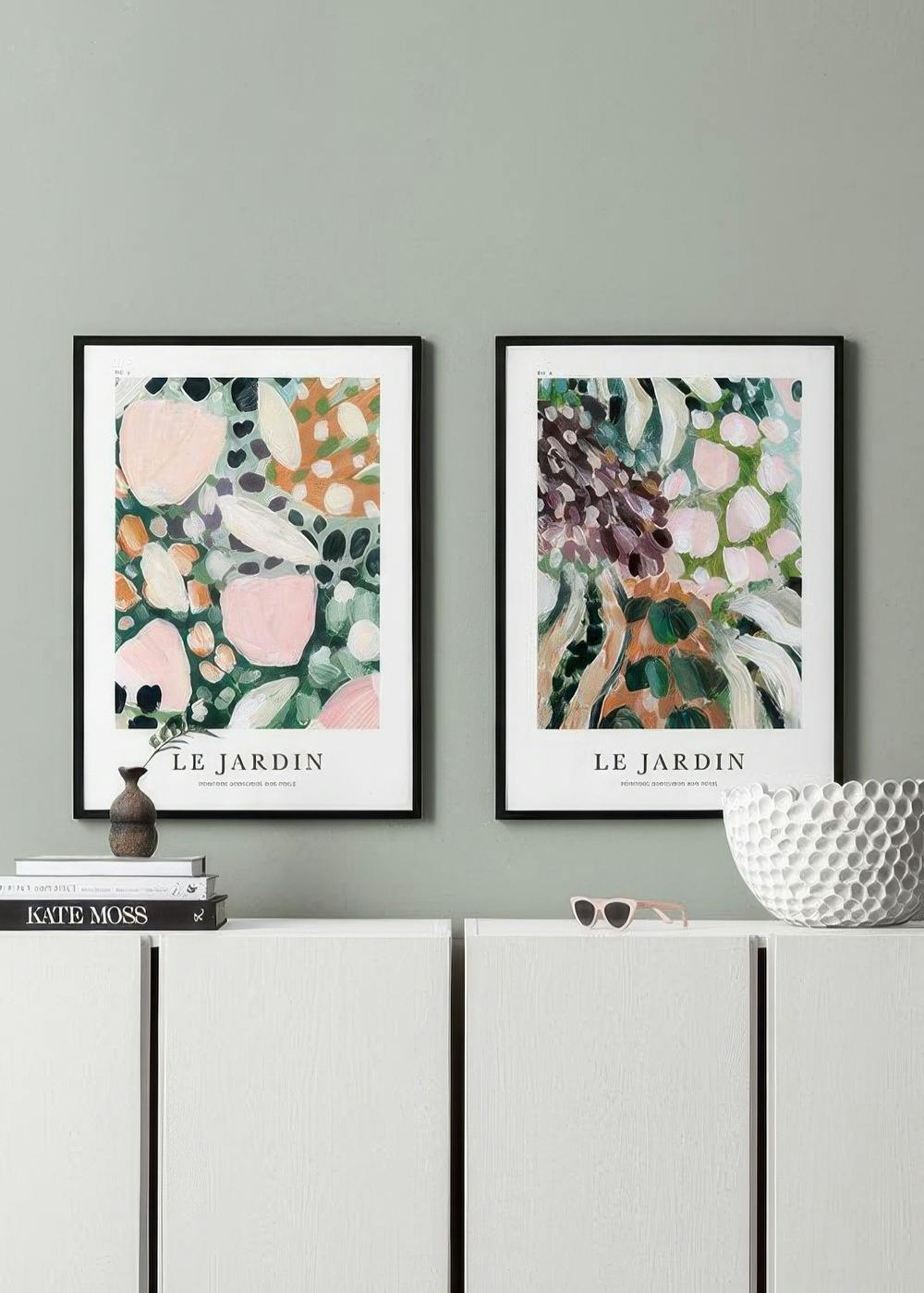 Kaksi abstraktia Le Jardin -julistetta, joissa on vaaleanpunaisia, oransseja ja vihreitä muotoja, muodostavat tauluseinän.