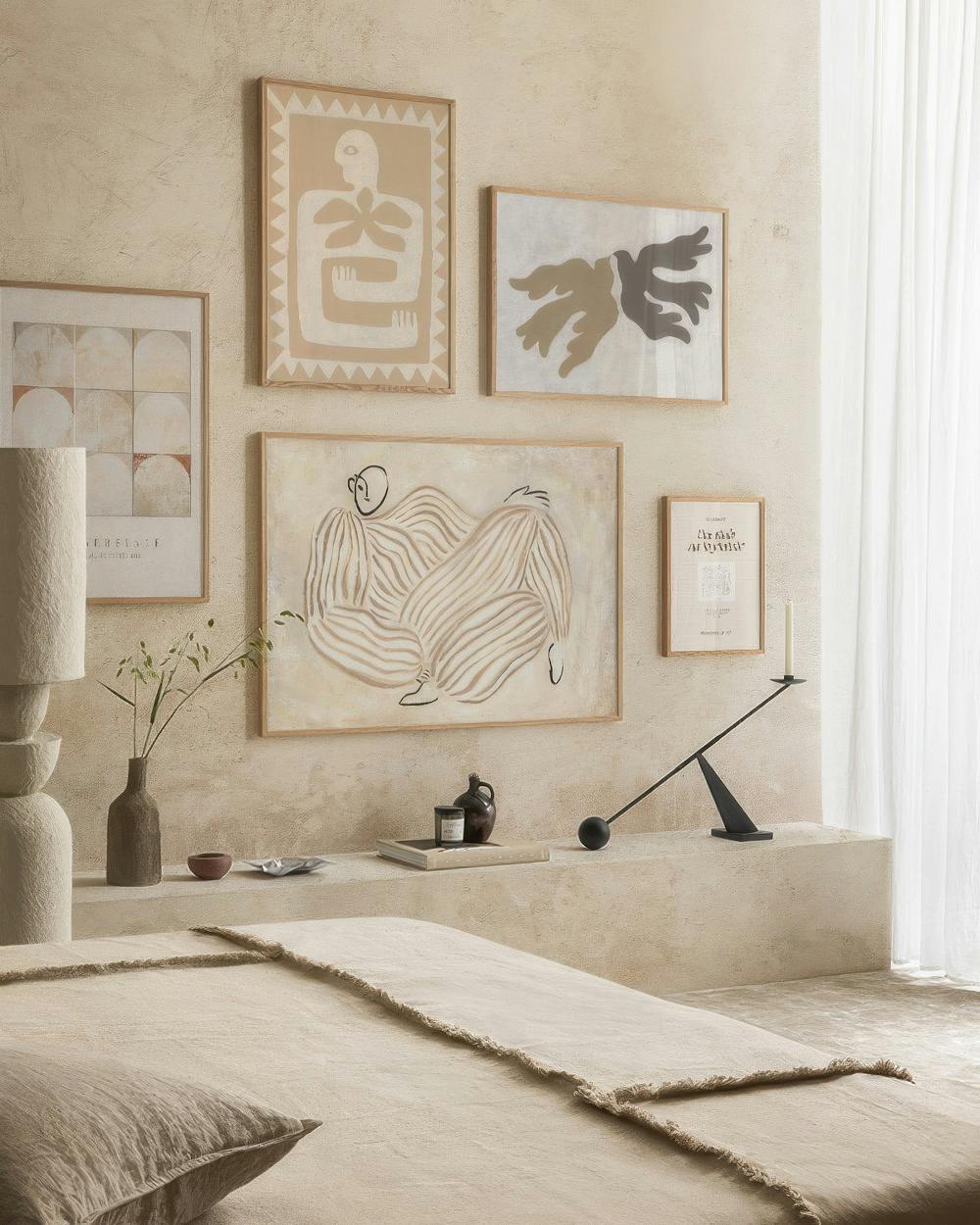 A gallery wall with abstract art featuring organic shapes, a reclining figure, and geometric patterns in earthy tones.