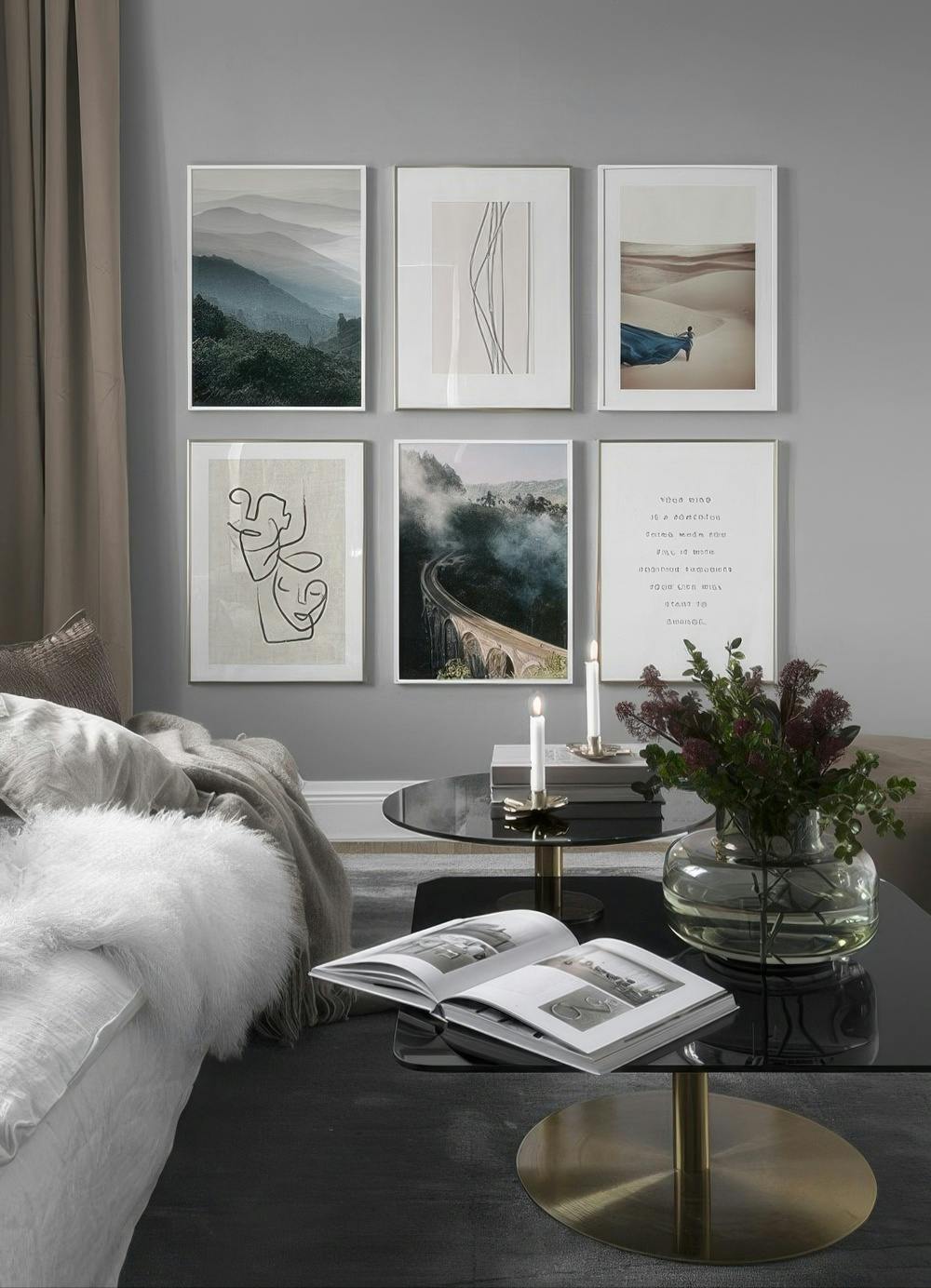 En tavelvägg med naturmotiv av berg, öken och en bro i dimma, samt grafiska linjemotiv och en texttavla.