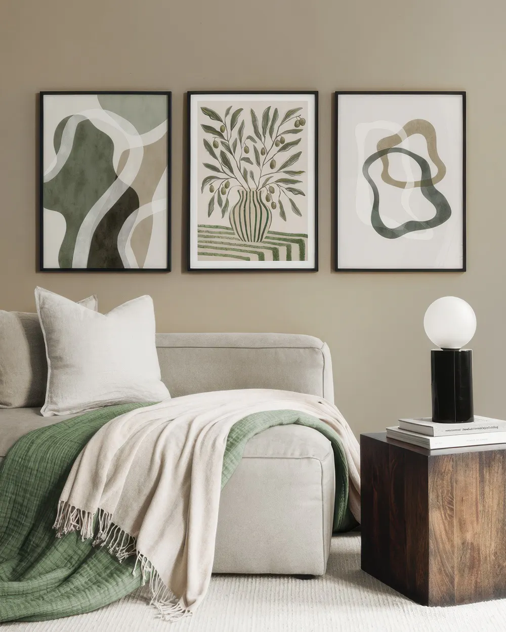 A poster pack featuring three contemporary art prints in muted green, beige, and white tones, above a sofa.
