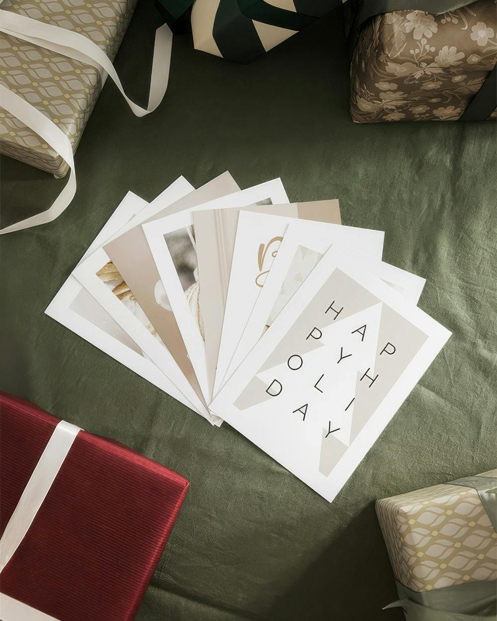 Paquetes de pósters con diseños de vacaciones en tonos neutros, rodeados de regalos envueltos.