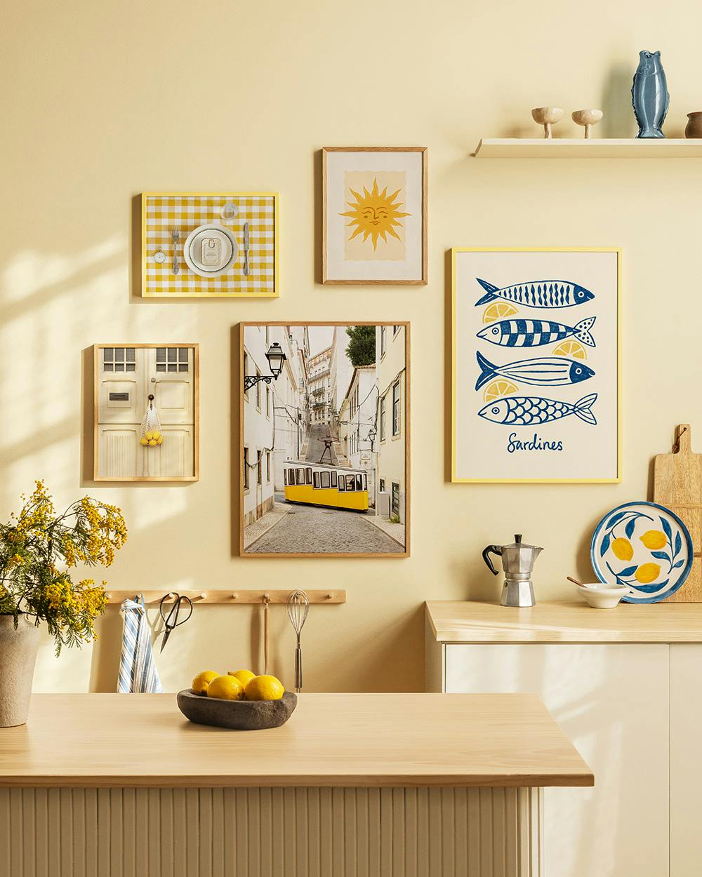 A gallery wall with a yellow gingham print, a sun face, a Lisbon tram street, a door, and a Sardines fish art print.