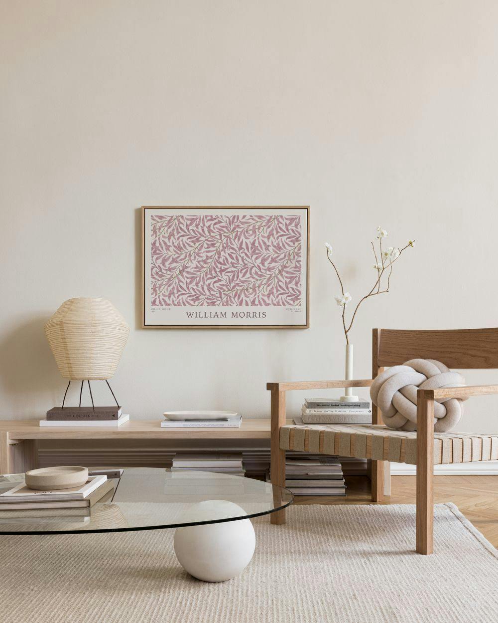 Toile William Morris à motif de feuilles rose pâle, suspendue au-dessus dun meuble bas dans un salon moderne.