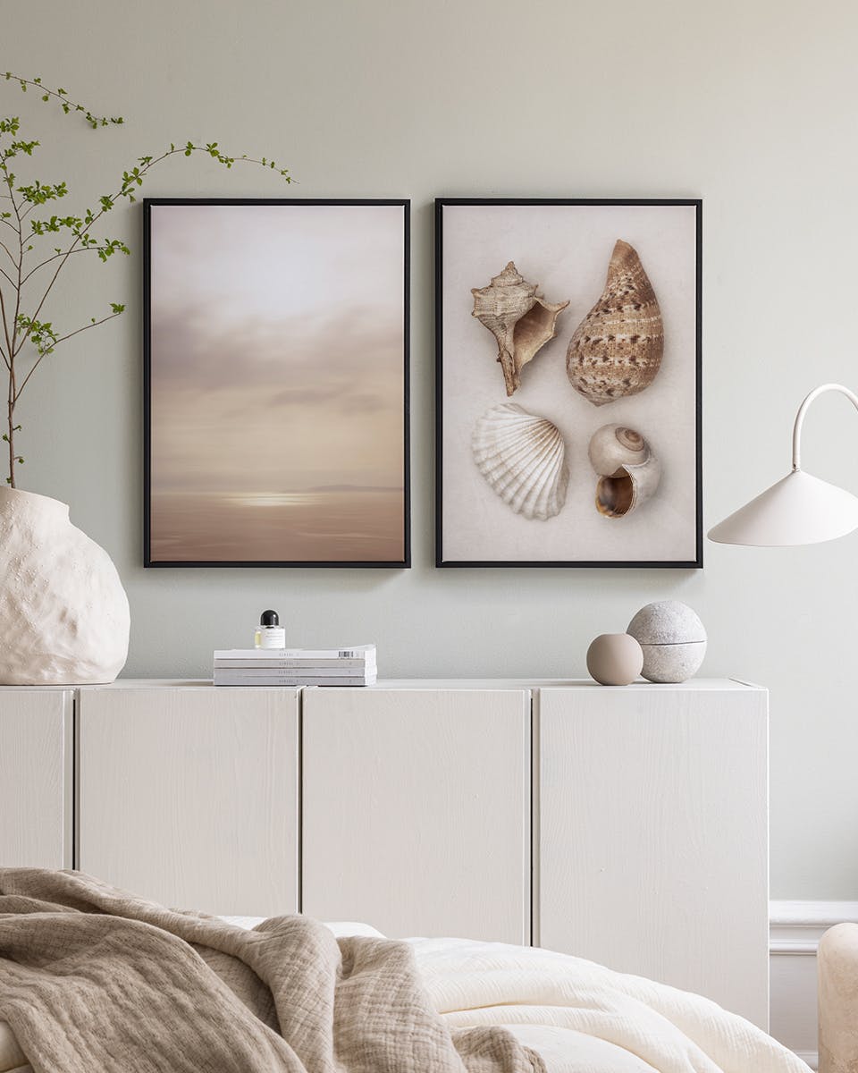 A poster pack displayed above a white dresser, featuring a serene beach landscape and natural seashells.
