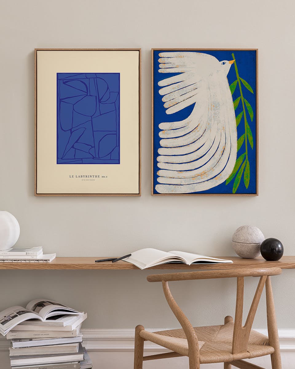 Lot de posters affichant un labyrinthe bleu et une colombe blanche avec une branche dolivier, sur un mur clair au-dessus dun bur