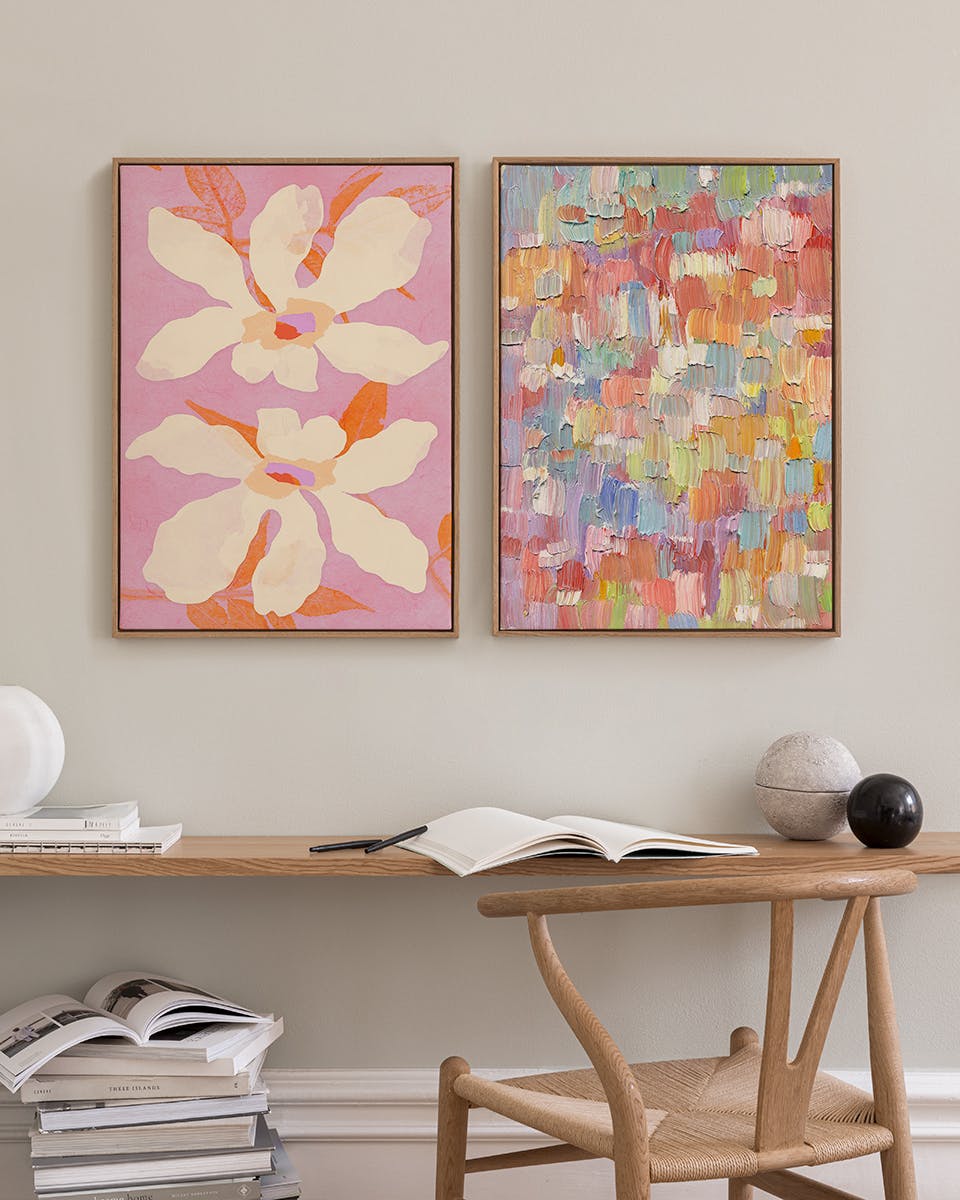 A poster pack displayed in a room, featuring a floral print with large white flowers on pink, and a colorful textured abstract p