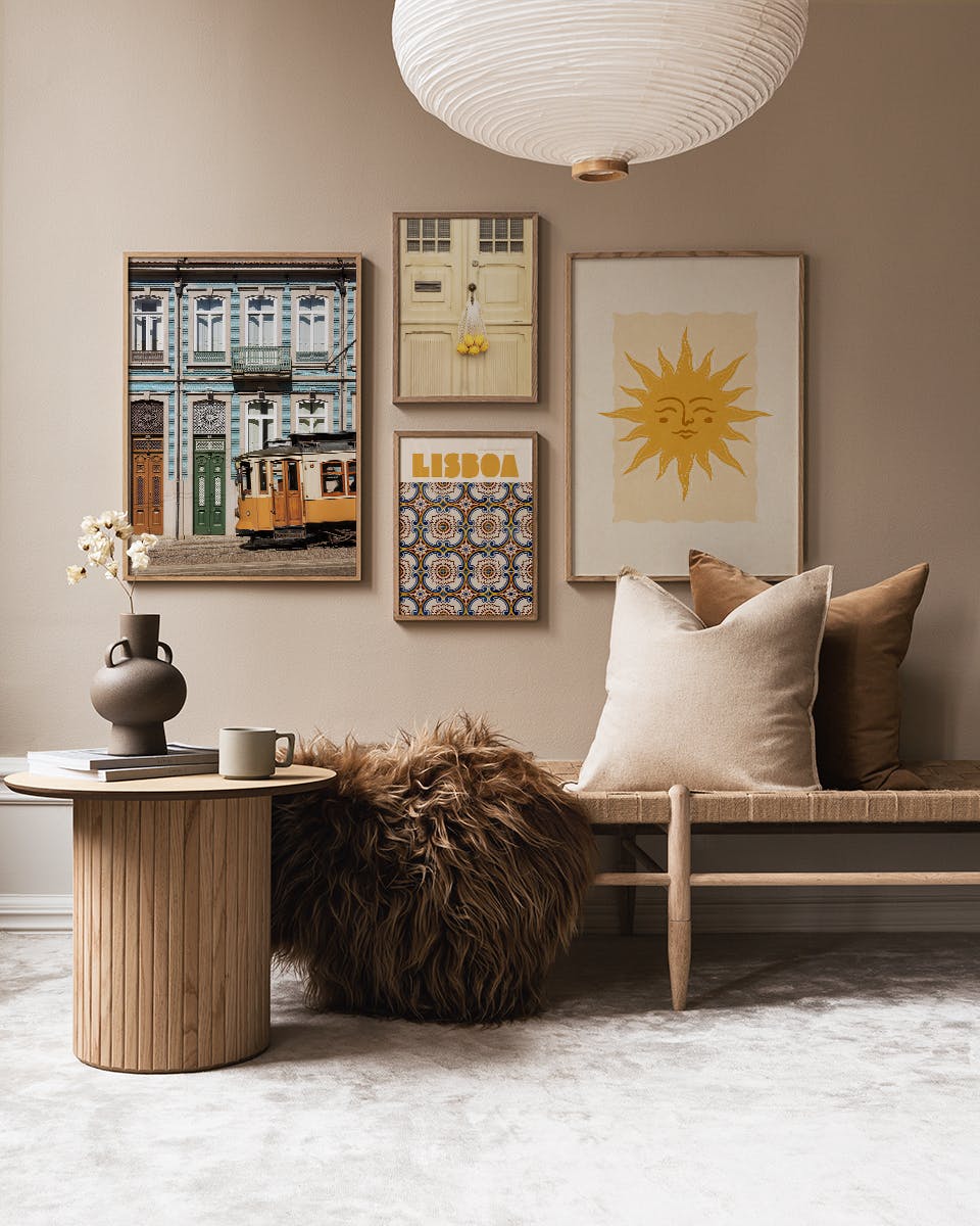 Vier postersets met Lisboathema aan een galeriewand, boven een houten bankje met kussens en een salontafel in een lichte kamer.