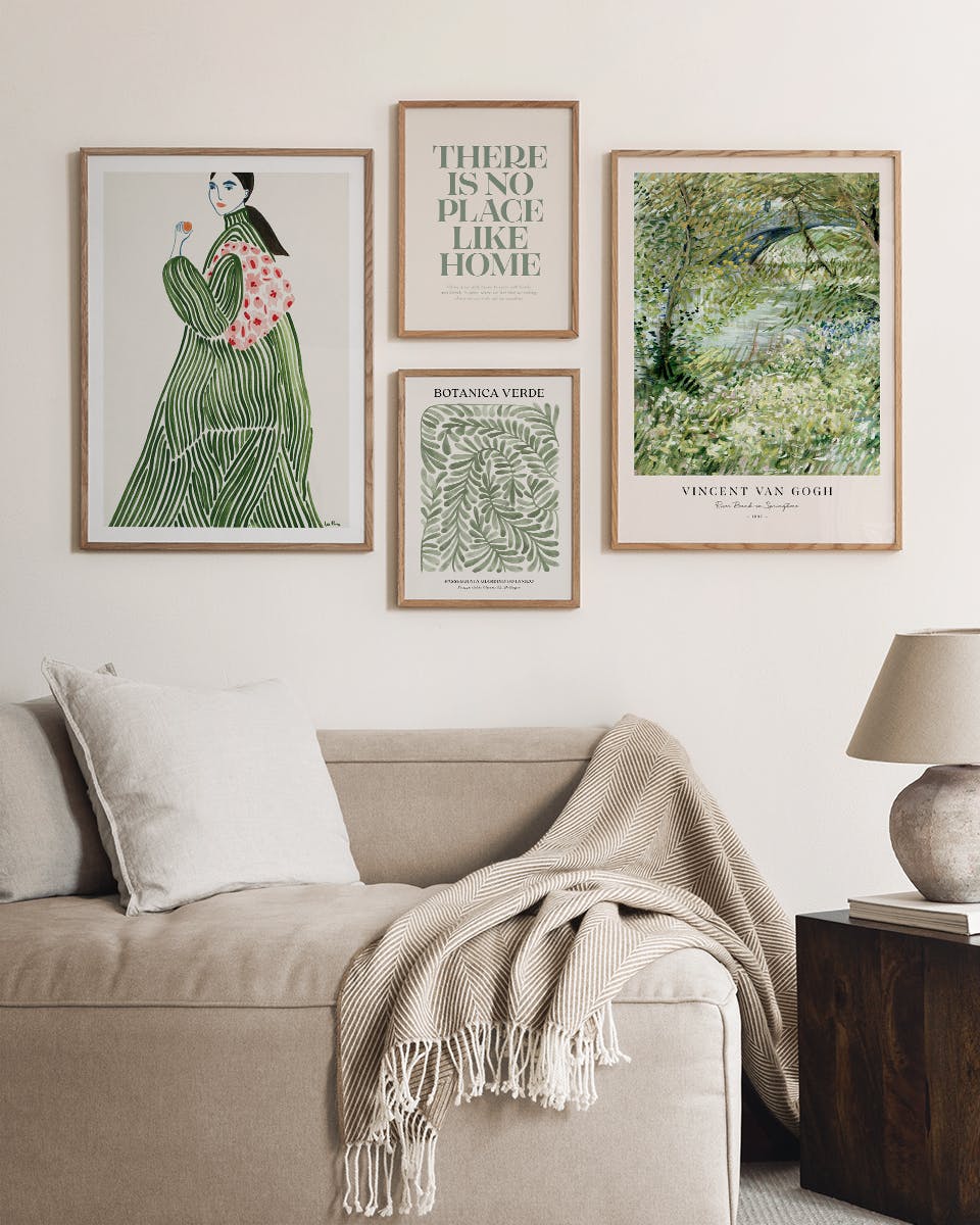 Neljä kehystettyä julistetta beigeillä seinillä olohuoneessa sohvan yläpuolella. Kaksi julistetta on pystyssä, kaksi vaaka-asenn