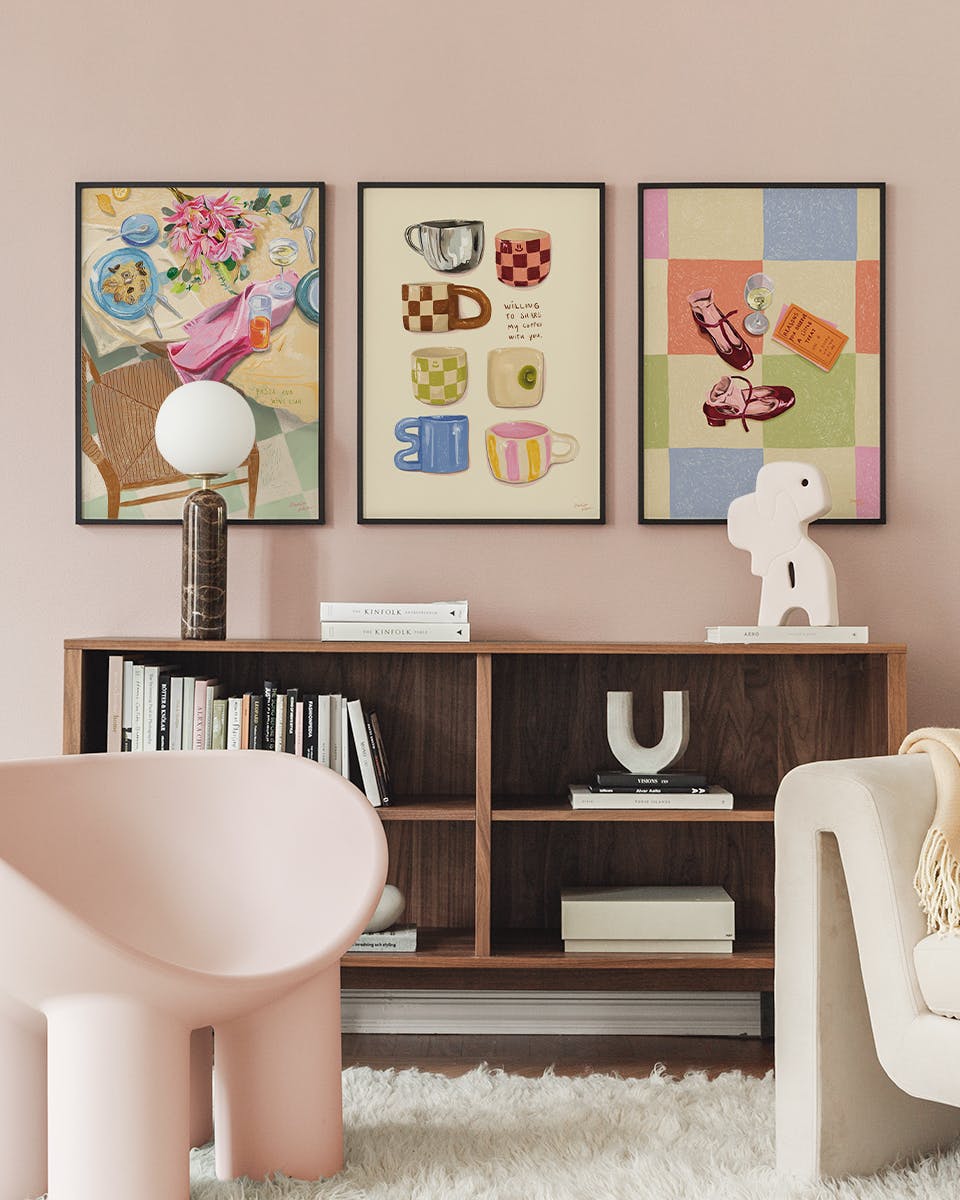 A poster pack of three art prints displayed as a gallery wall above a wooden bookshelf in a modern living room.