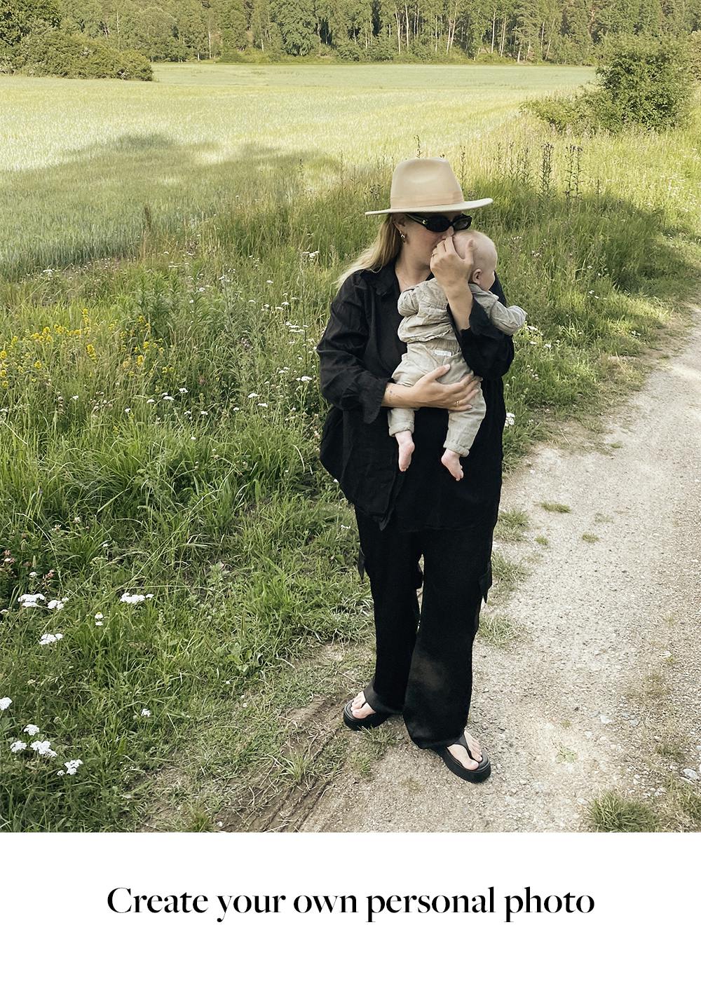 Par i omfavnelse, set bagfra, kigger ud over et naturlandskab. Kvinde med blond hår og hat læner sig mod manden.