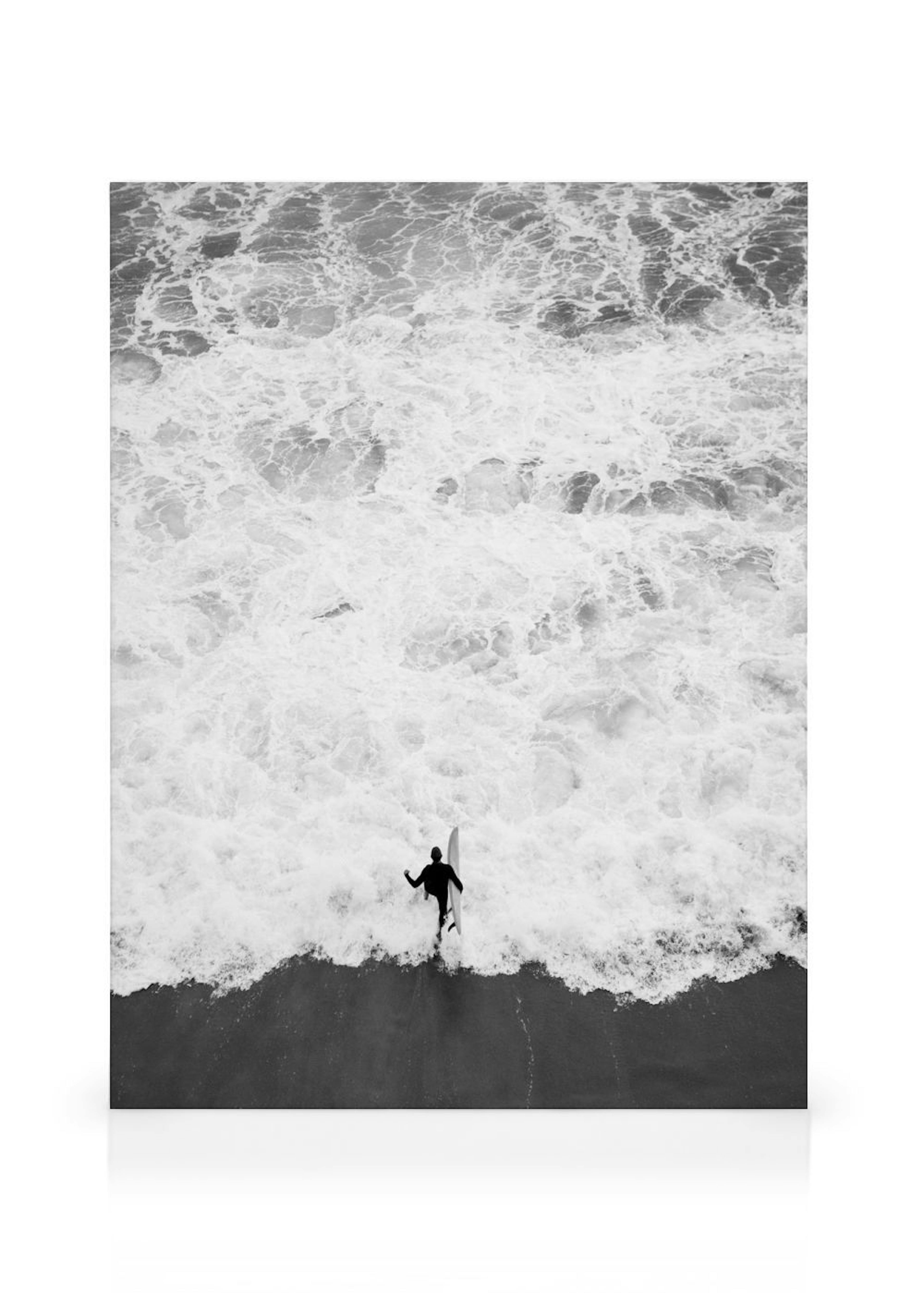Leinwandbild: Schwarz-weiß-Foto eines Surfers mit Brett, der im schäumenden Meer steht.