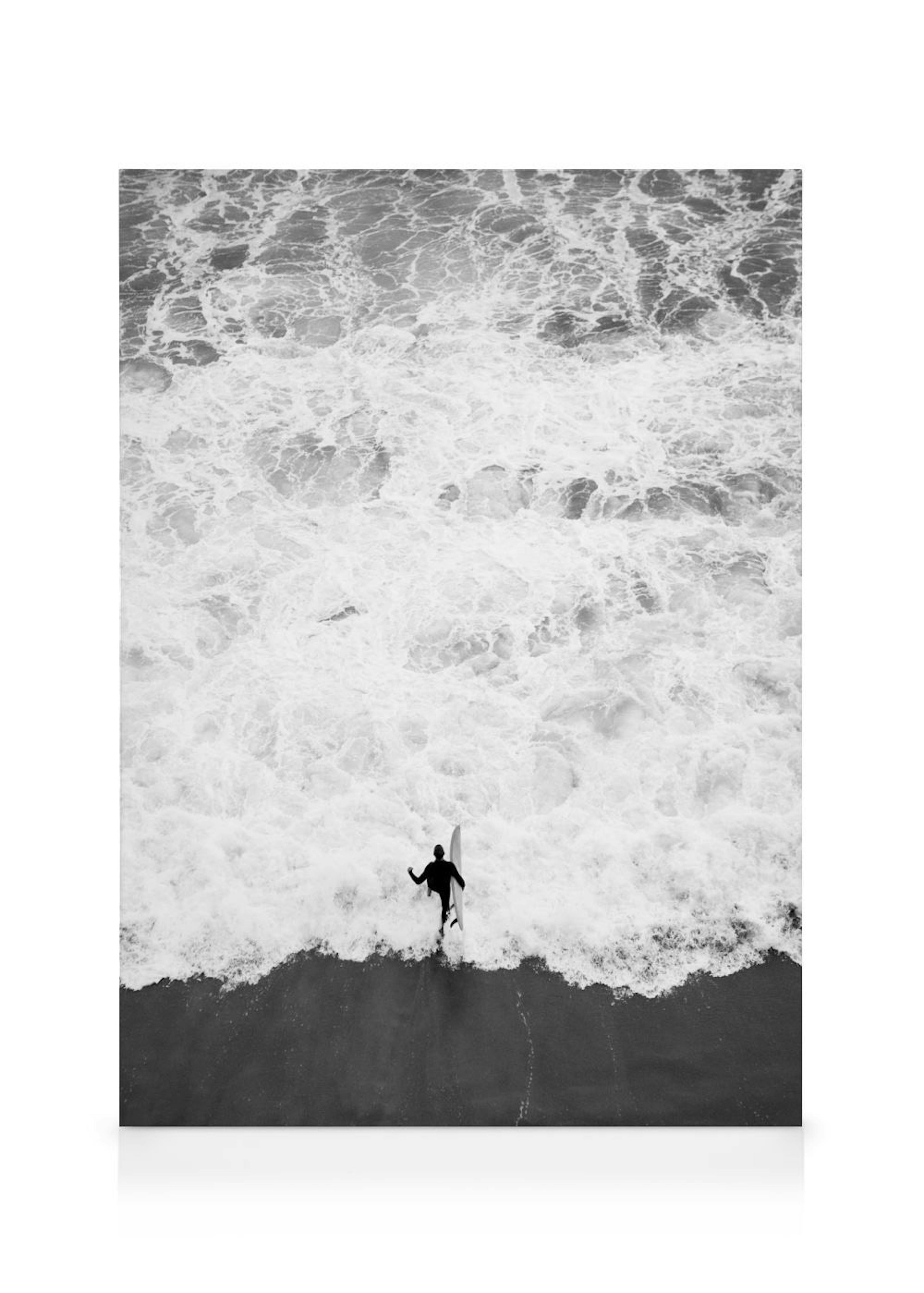 Leinwandbild eines Surfers in Schwarz-Weiß, der mit seinem Brett an einem schäumenden Meer am Strand steht.