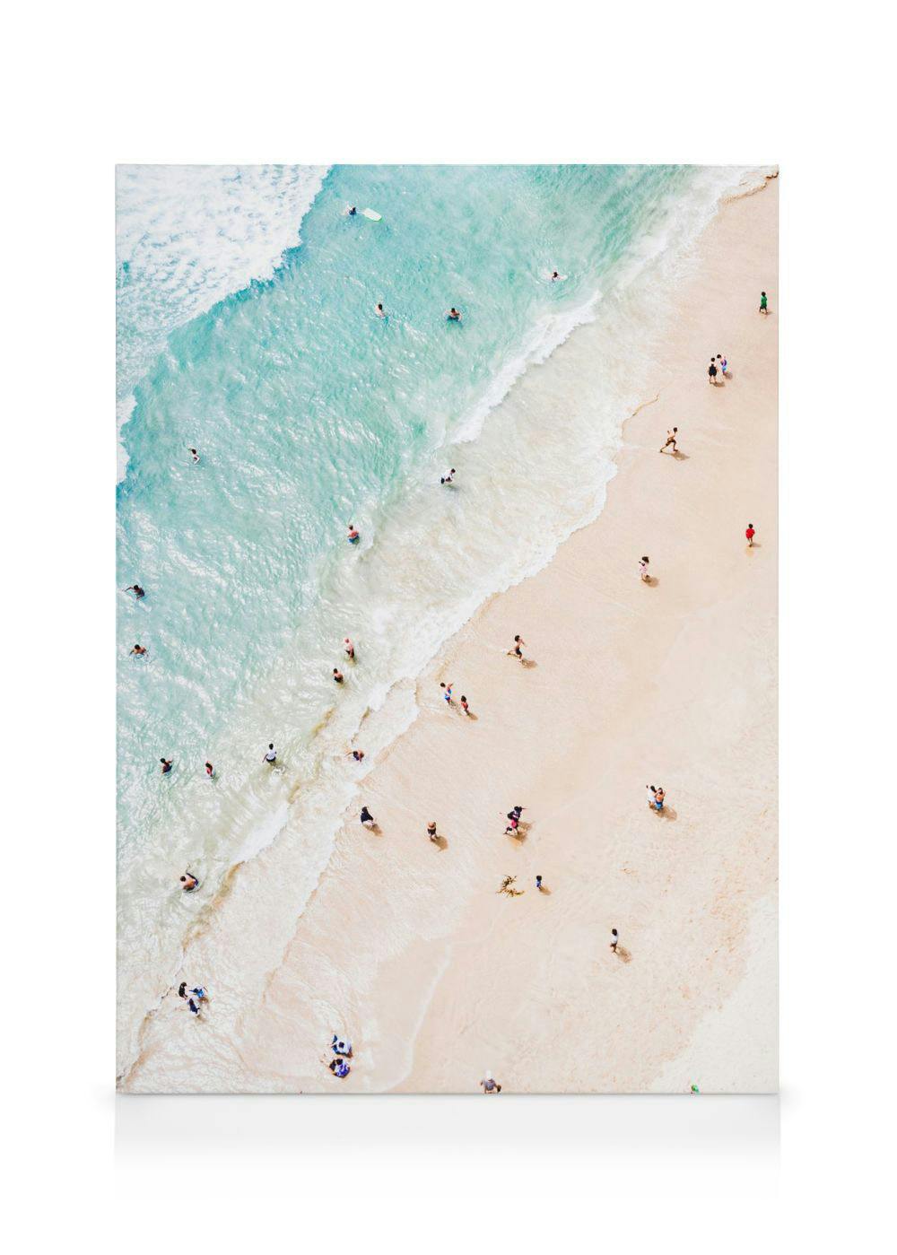 Lienzo de una playa de arena dorada y agua turquesa con bañistas, vista aérea.