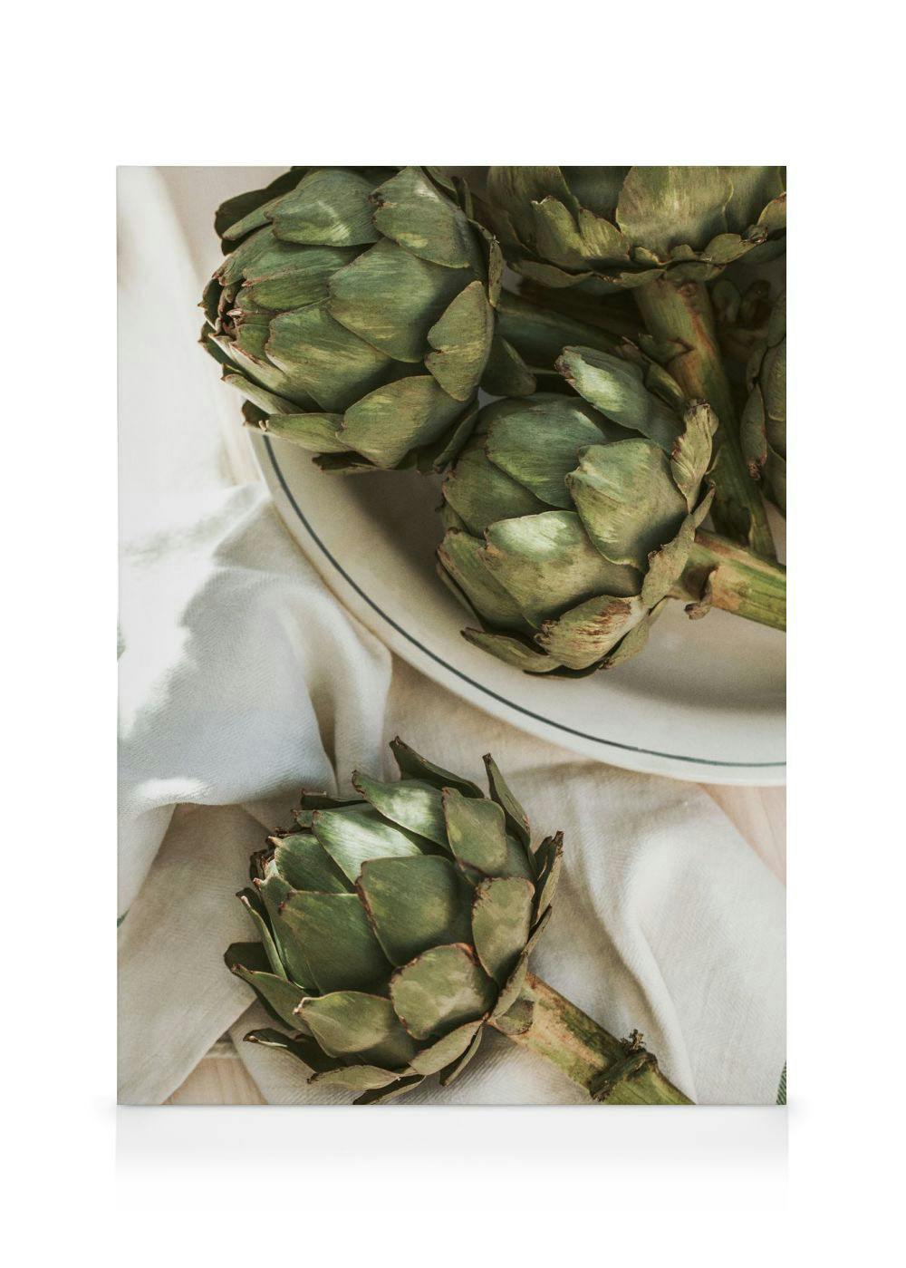 Leinwandbild mit Artischocken auf einem Teller und Leinentuch in grünen und beigen Tönen.