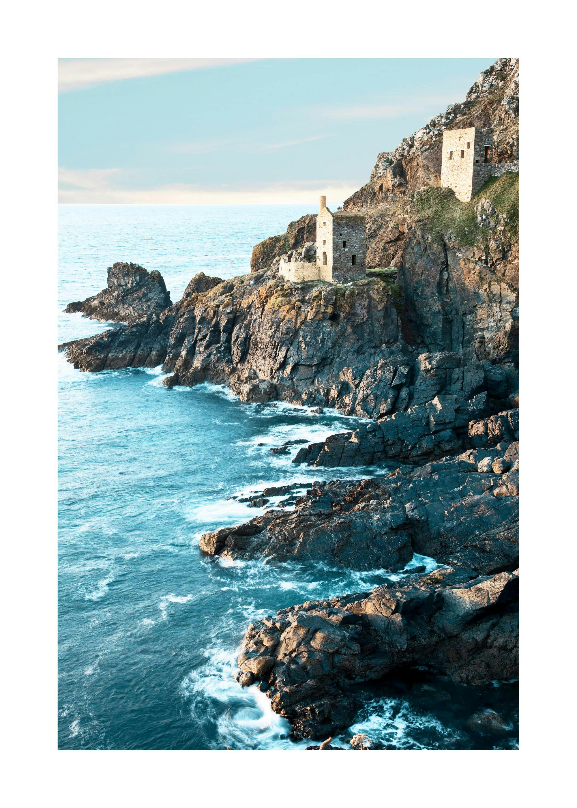 Fotografi av den klippiga kusten vid Botallack i norra Cornwall med gamla tenngruvor och blått hav.