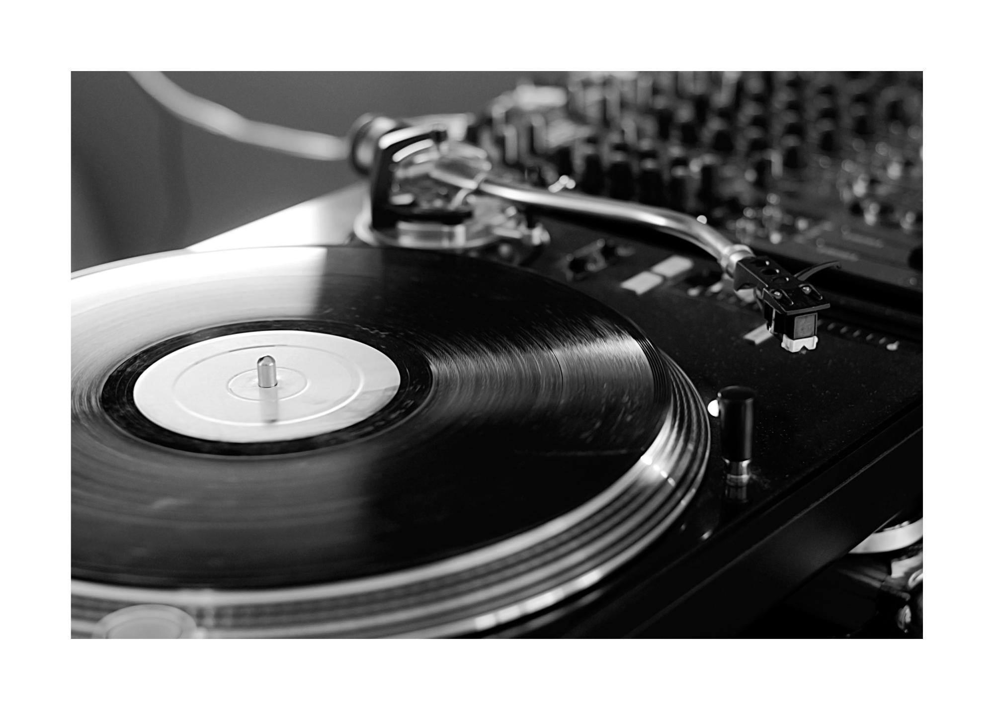 Czarno-biały plakat gramofon z płytą winylową i igłą, w tle sprzęt DJ-ski, muzyka, styl retro