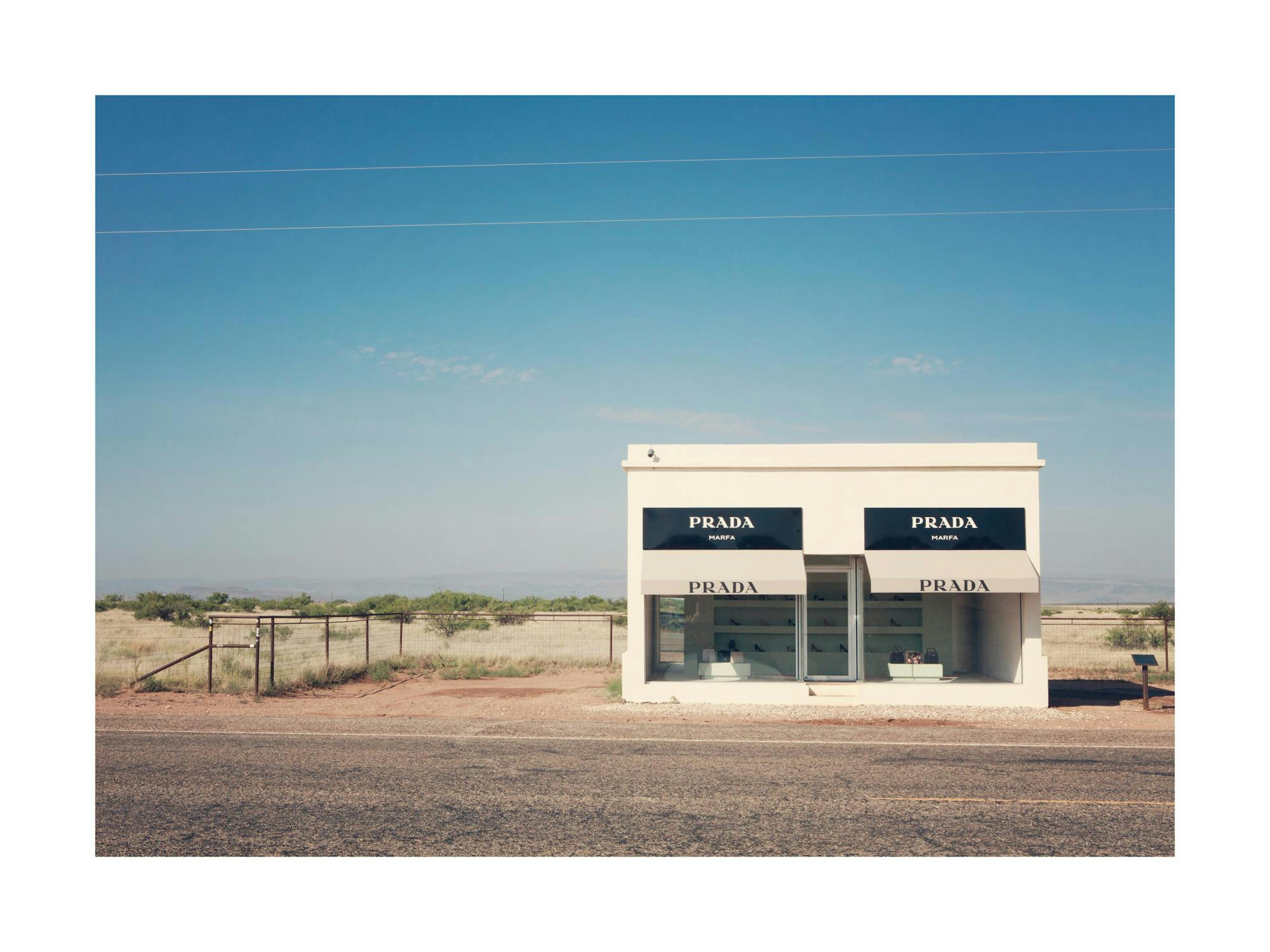 Póster Prada Marfa, tienda ficticia en desierto de Texas bajo cielo azul claro.