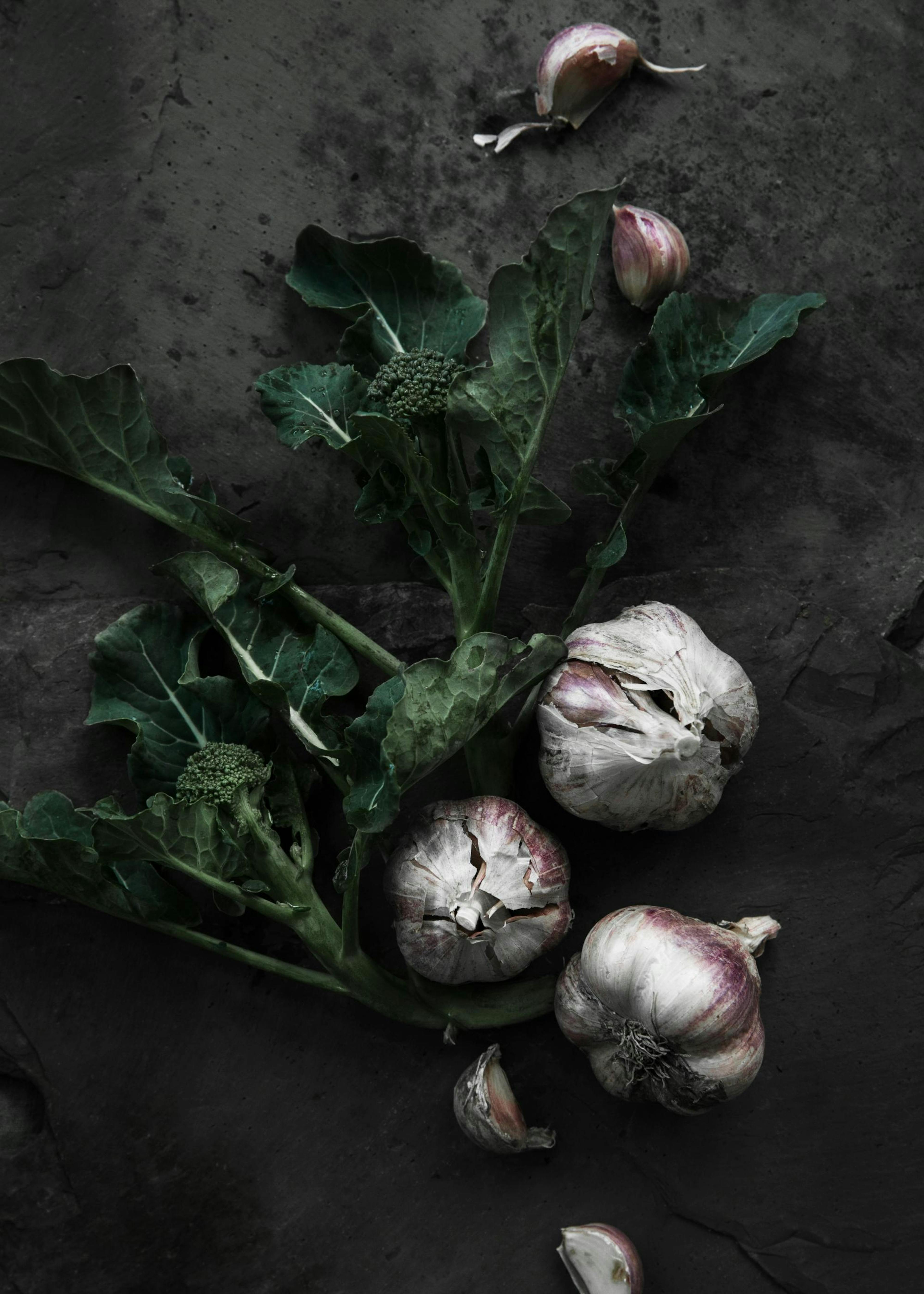 Brokolice a česnek na tmavém pozadí, kulinářský plakát s rostlinnými prvky.