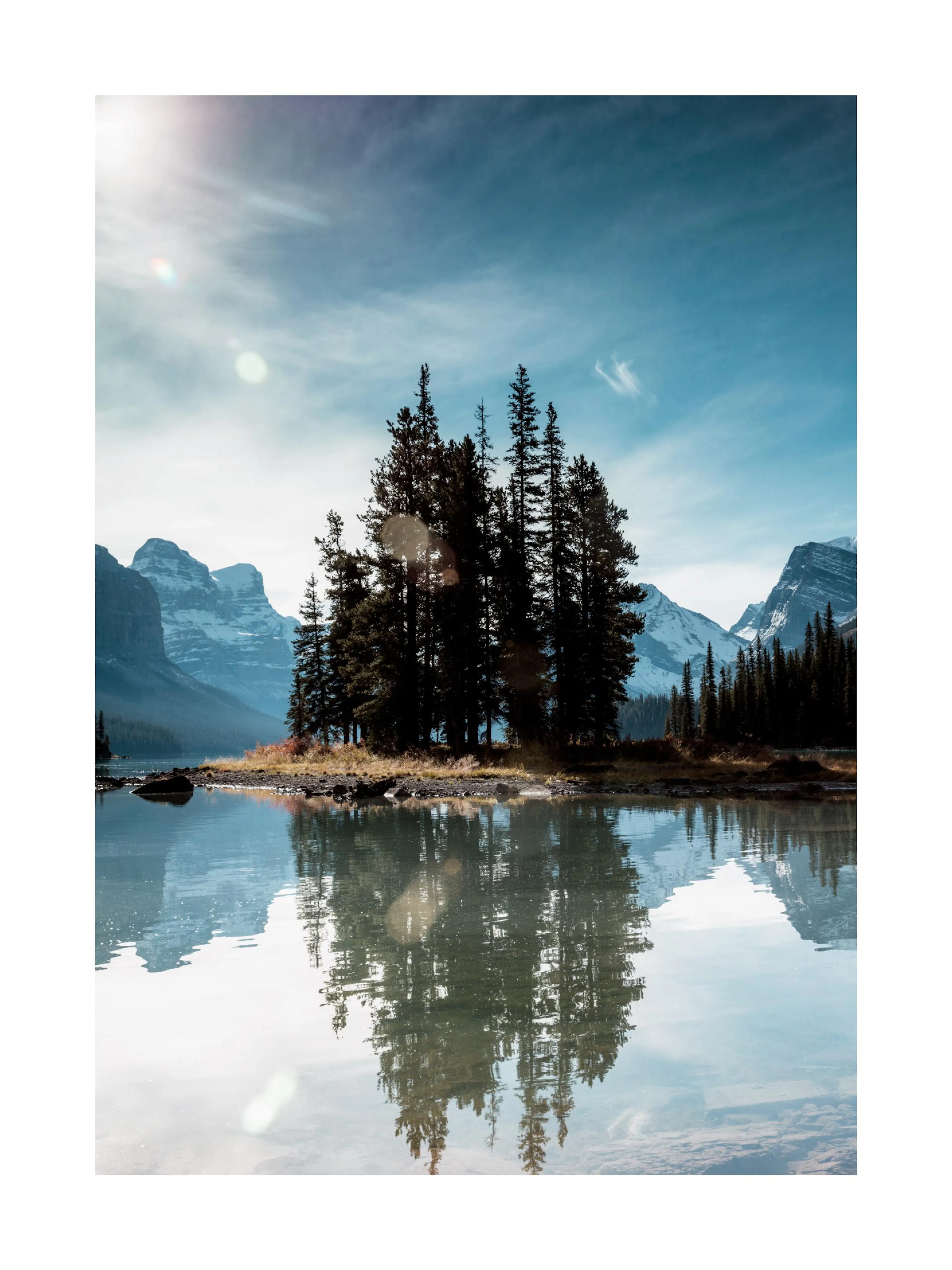 Póster de Spirit Island con isla boscosa reflejada en el lago, montañas nevadas y cielo azul. Ideal para decoración de hogar.