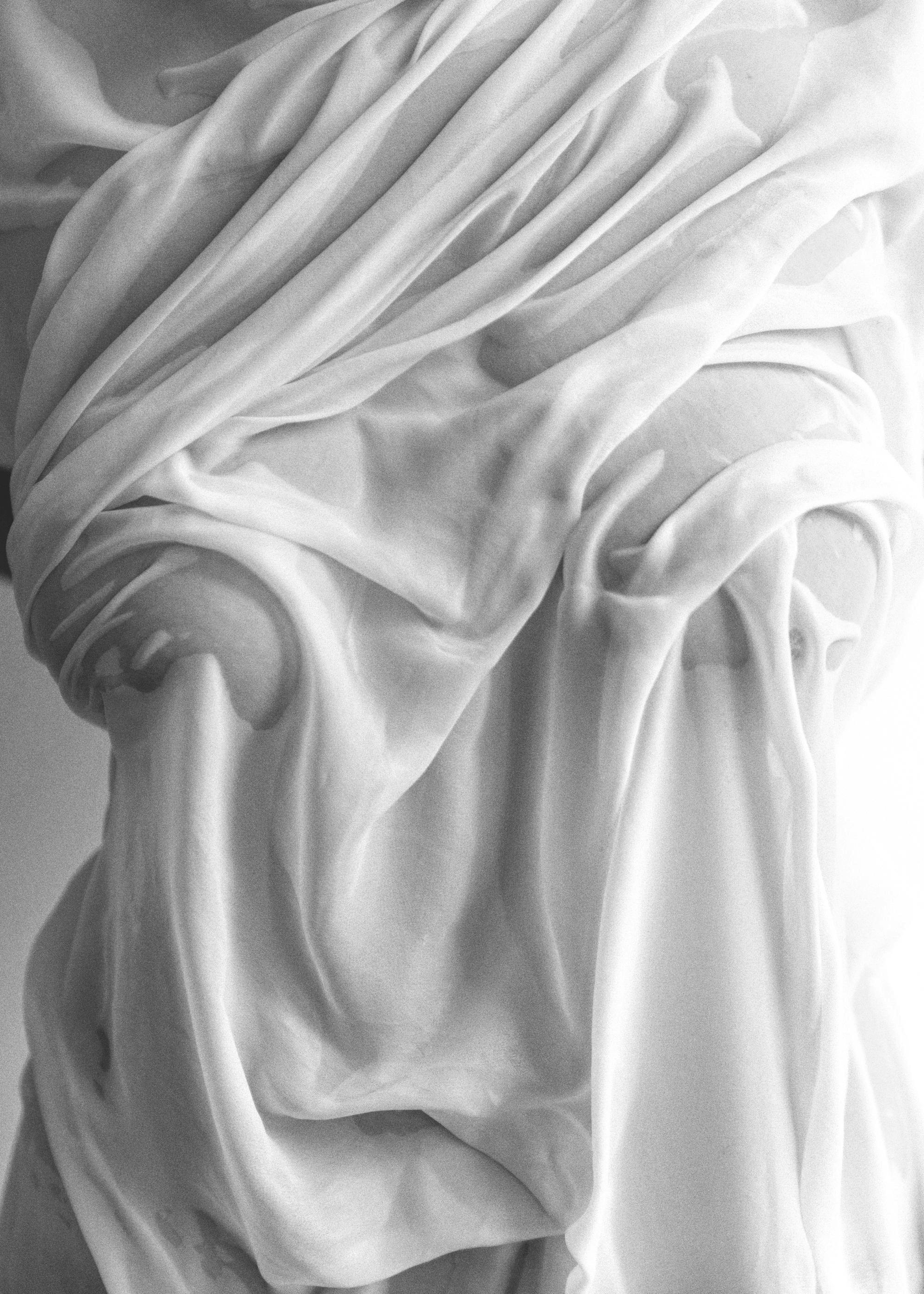 Svartvit fotokonst av våt, draperad vit textil som framhäver tygets veck och struktur. Perfekt för modern inredning.