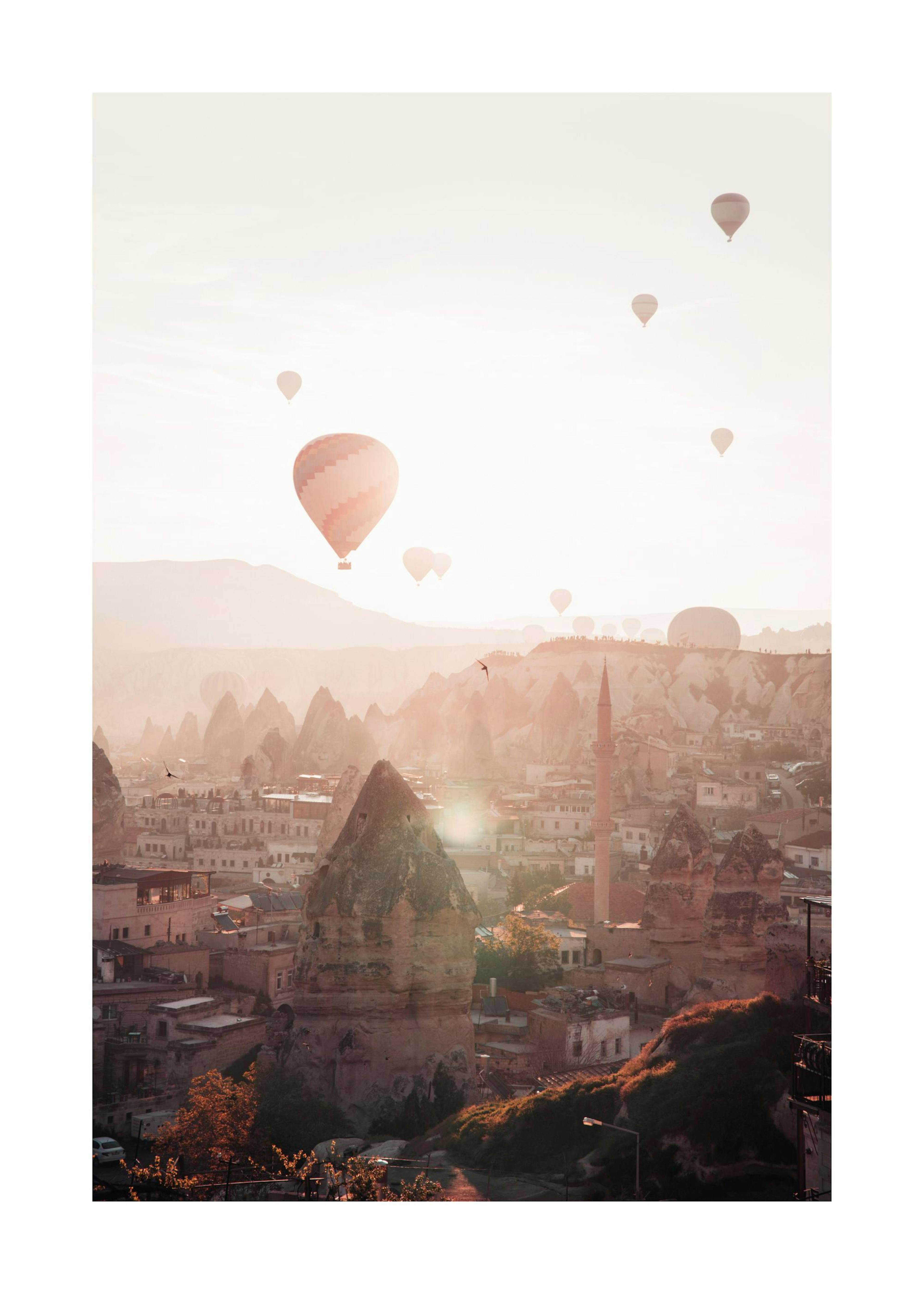 Balony na tle zachodzącego słońca nad miastem Kapadocja, Turcja. Pastelowe niebo, góry, minaret, budynki.