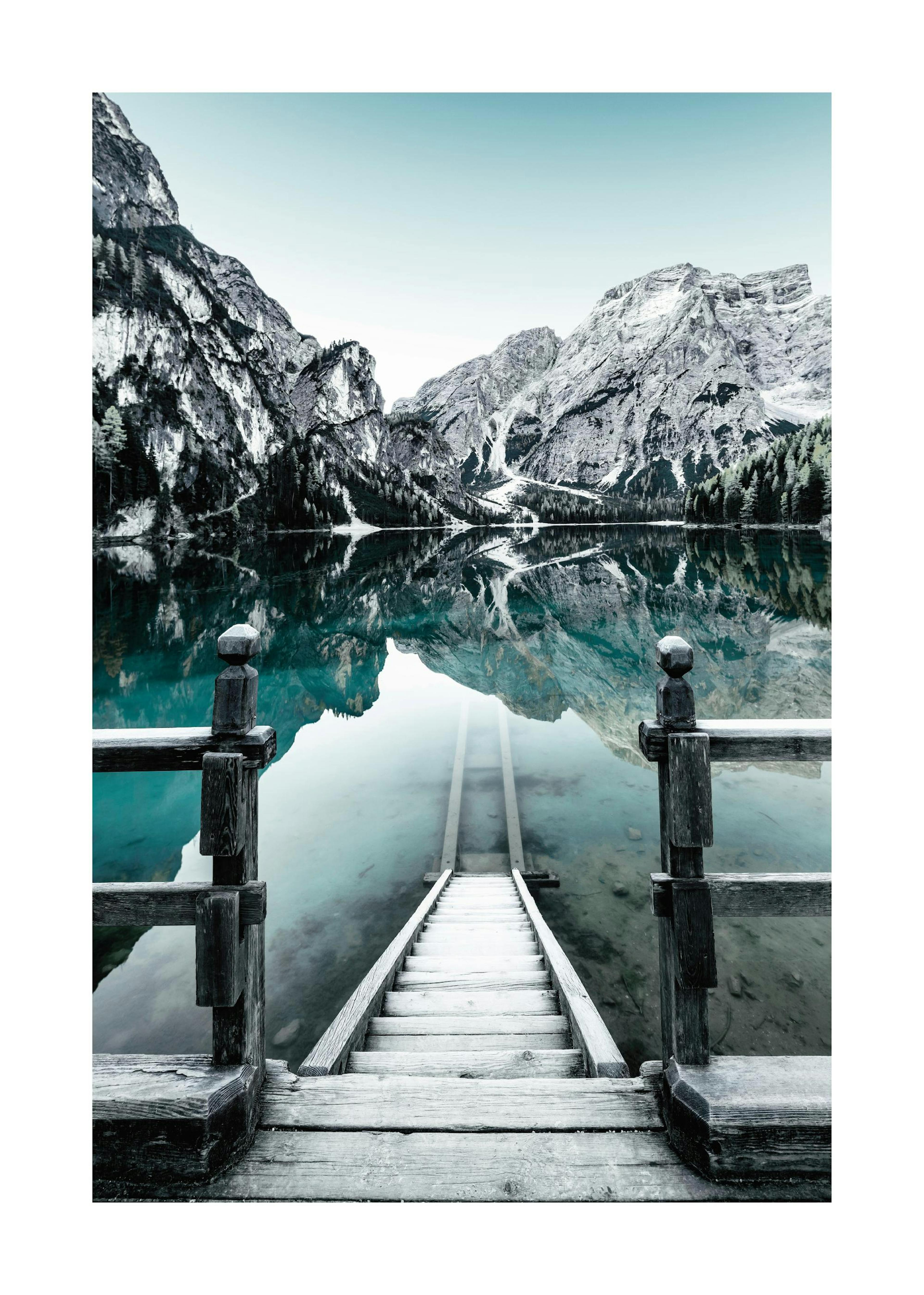 Póster del lago Braies con una escalera de madera que se adentra en las aguas claras, rodeada de montañas nevadas en Italia.