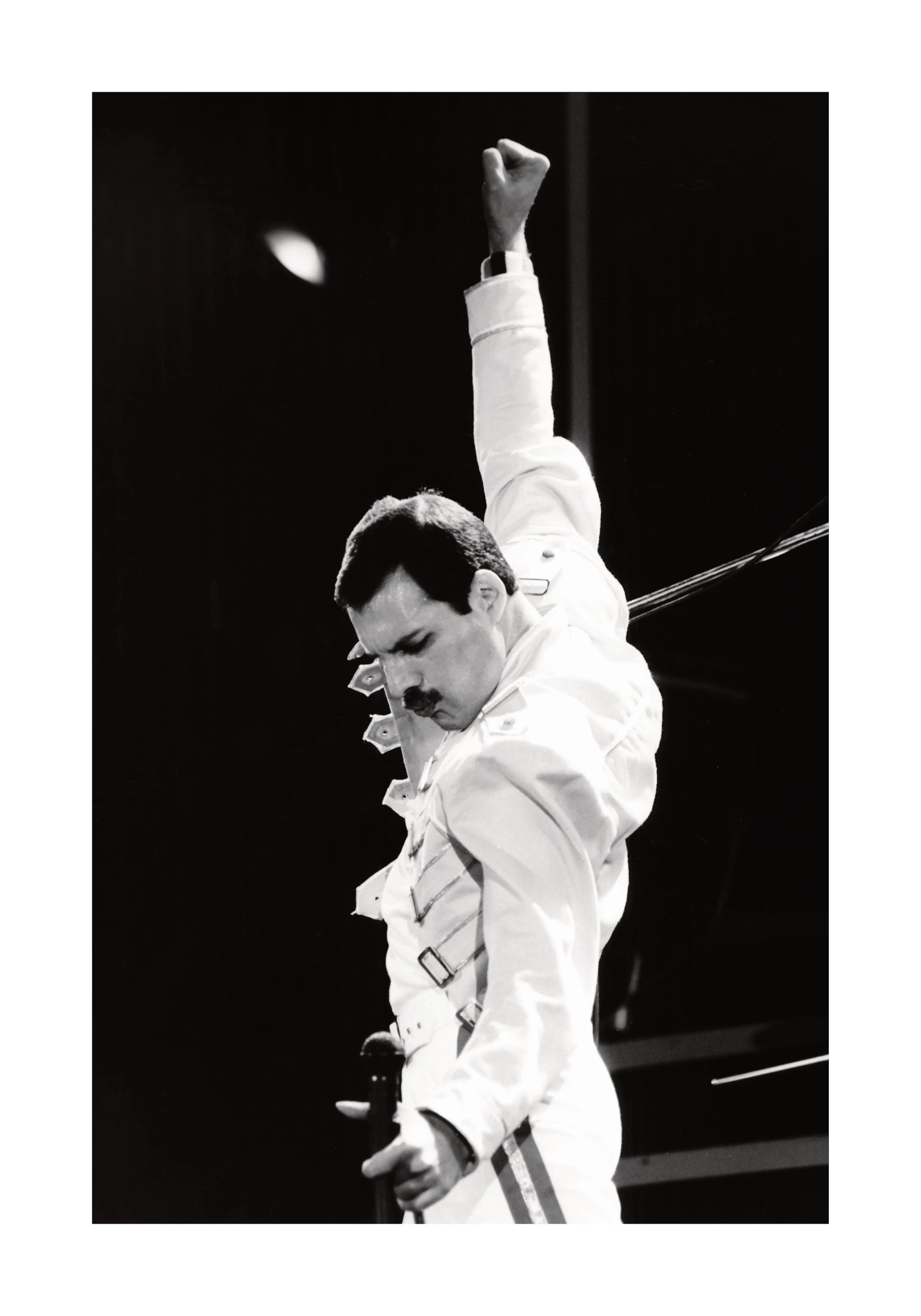 Póster de Freddie Mercury de Queen en blanco y negro, con traje blanco, micrófono y brazo alzado.