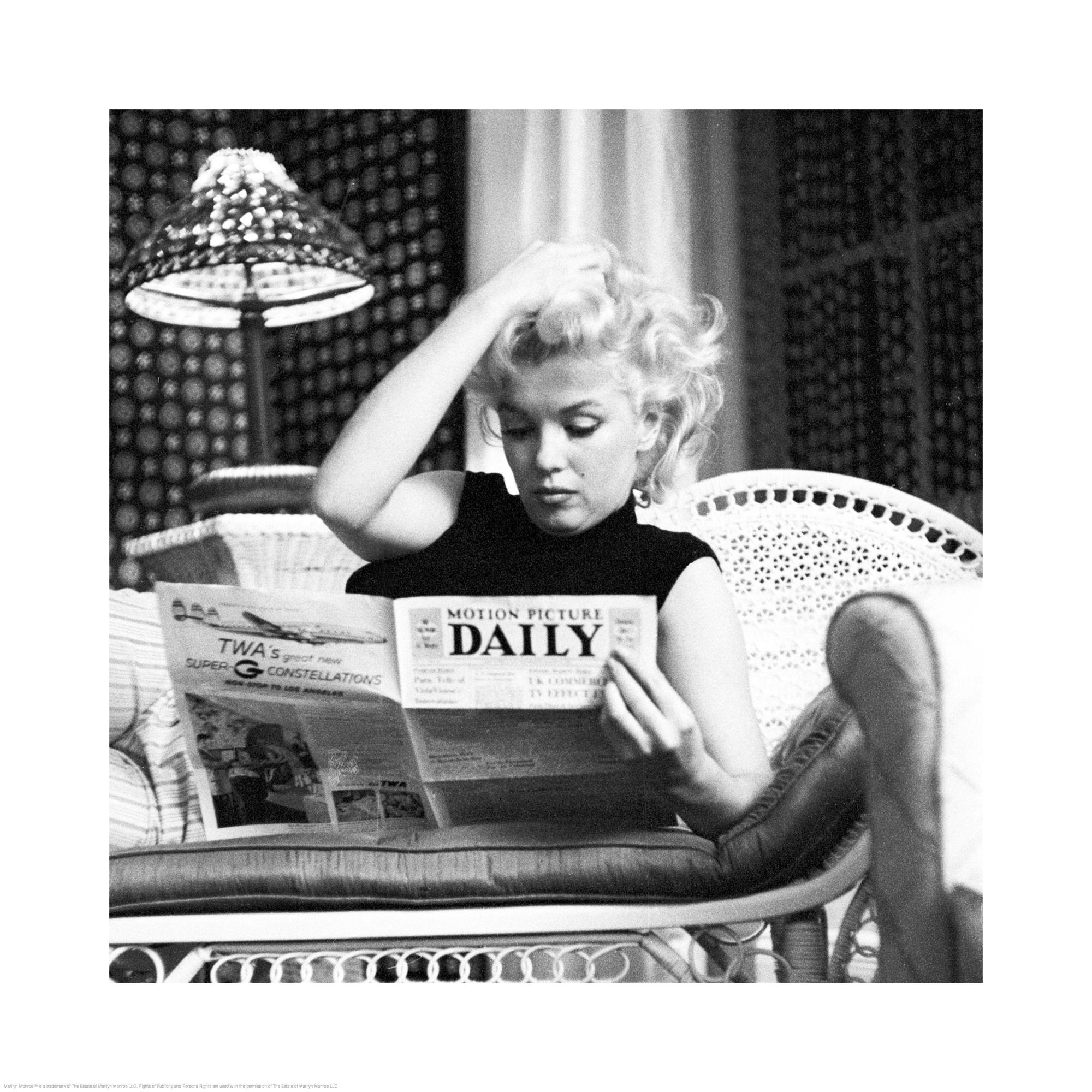 Svartvitt fotografi av Marilyn Monroe som läser tidning i soffa, ikonisk bild, filmstjärna.