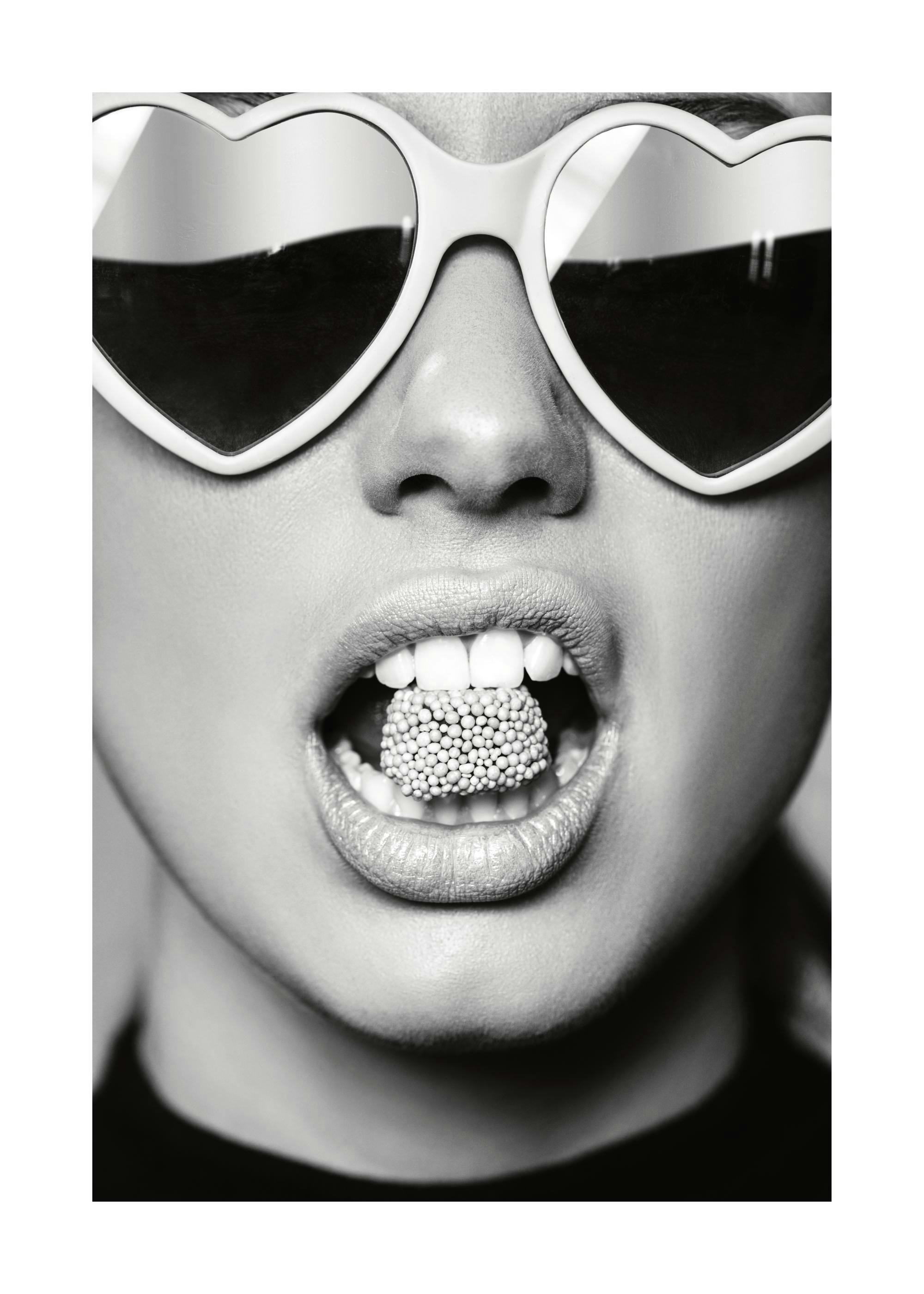 Affiche noir et blanc, bouche ouverte avec des bonbons et lunettes de soleil en forme de cœur.