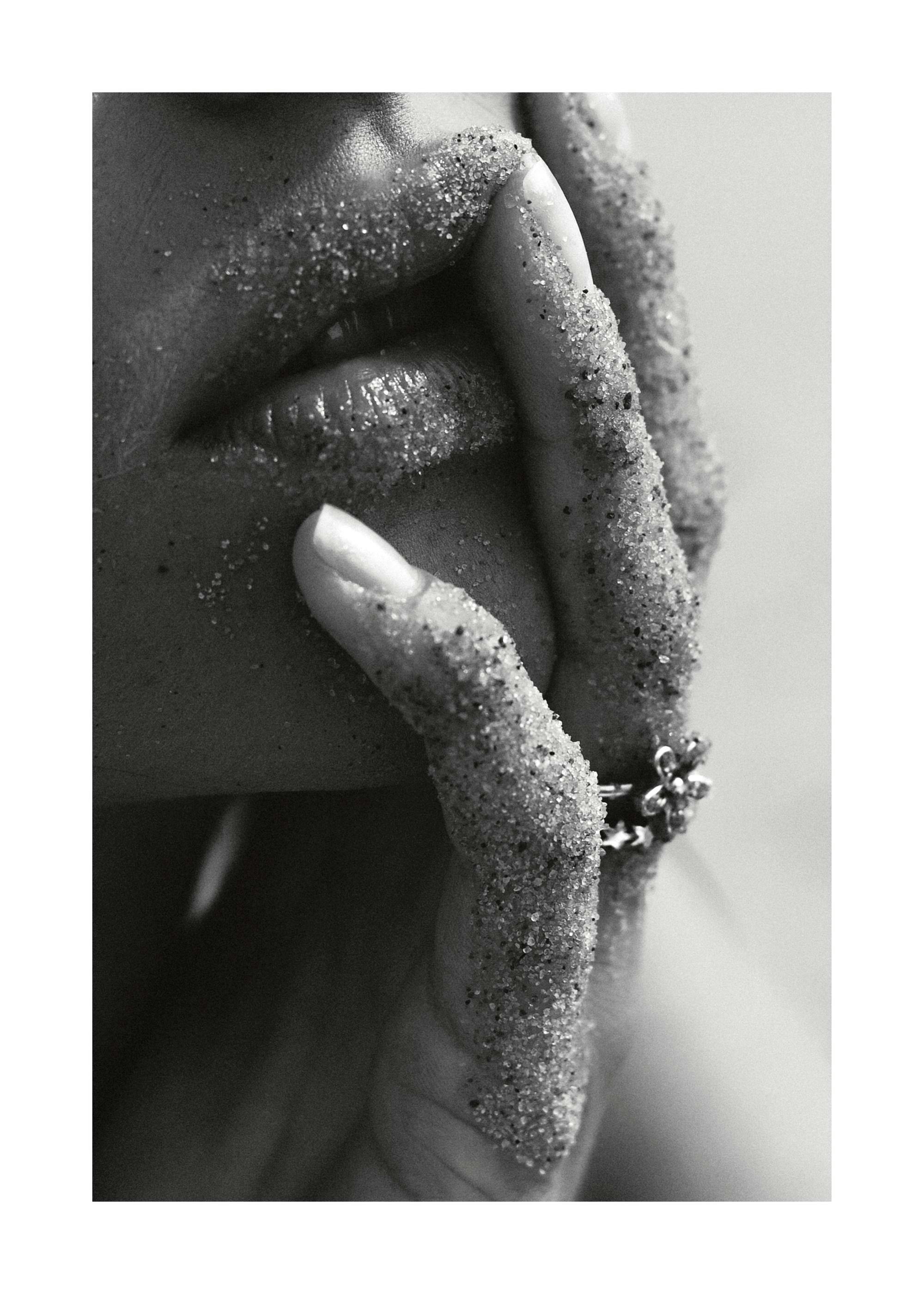 Black and white photograph of a womans sandy fingers and lips, creating a sensual art print.