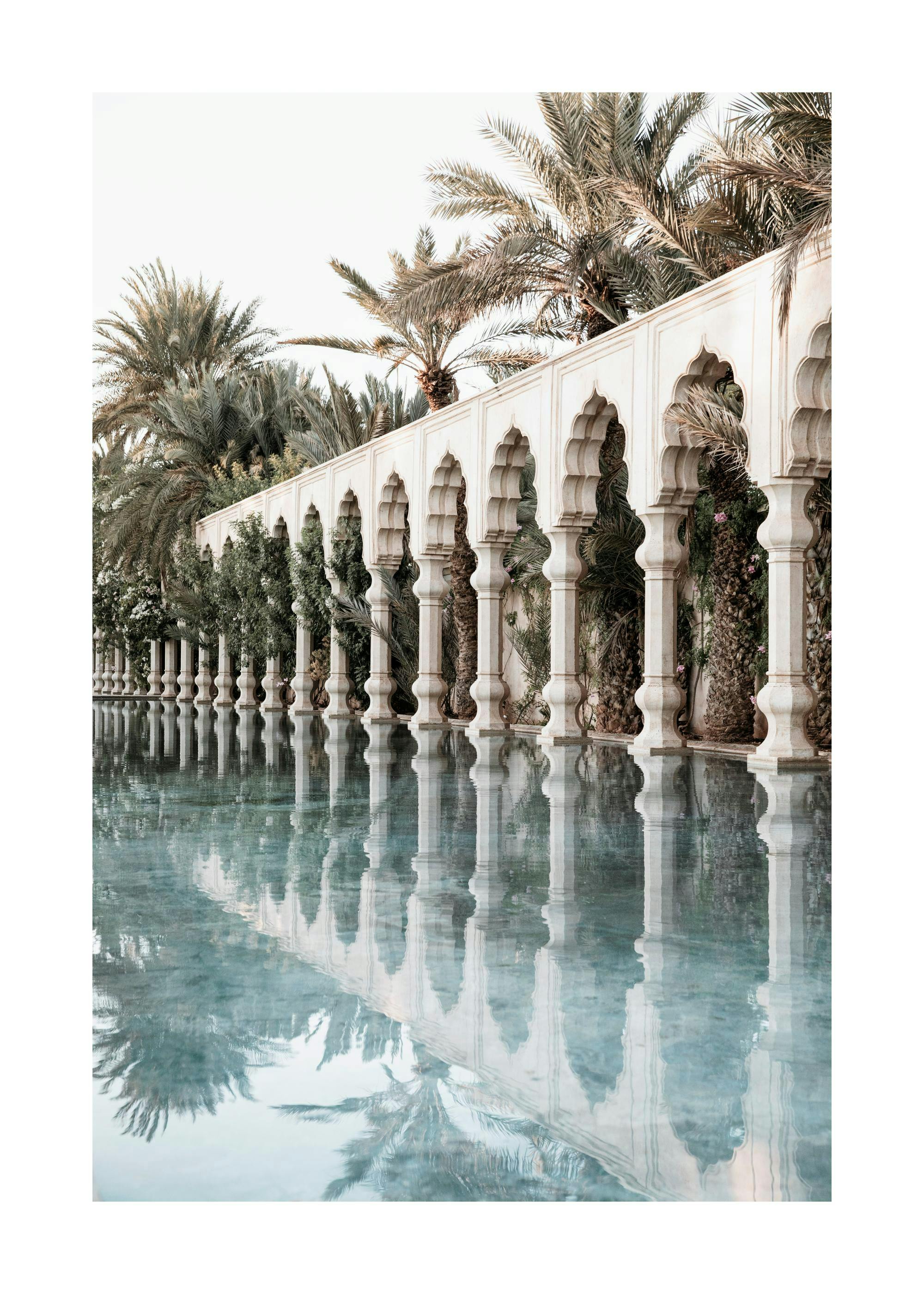 Affiche photographique de piliers blancs et arches arrondies se reflétant dans une piscine avec des palmiers
