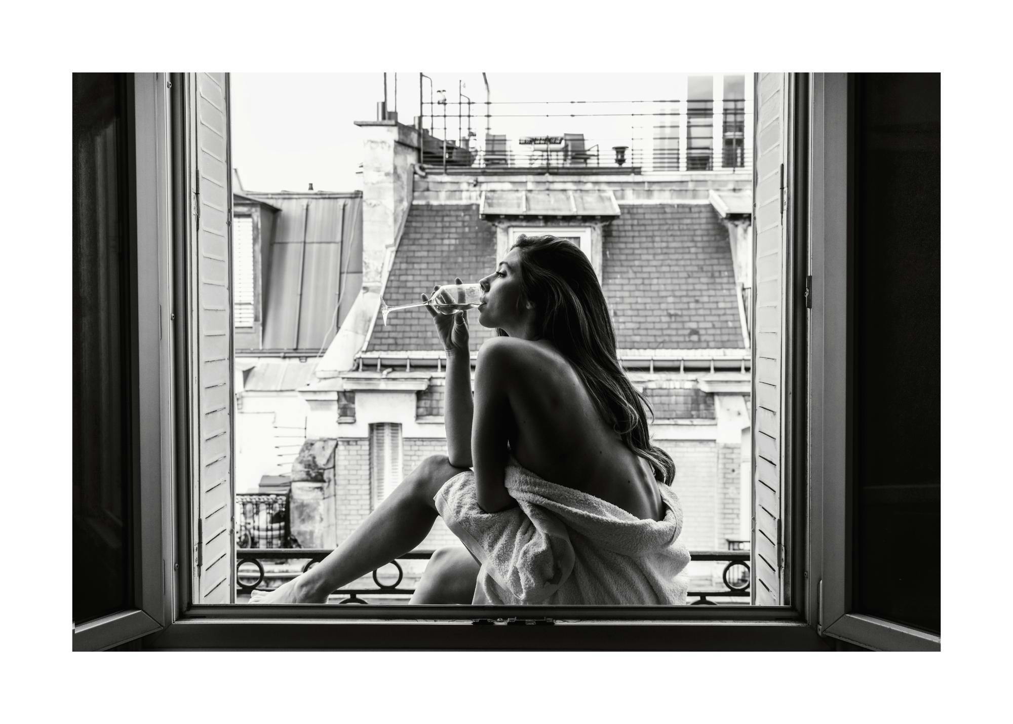 Black and white print of a woman in a towel sipping wine in a window, a timeless poster.
