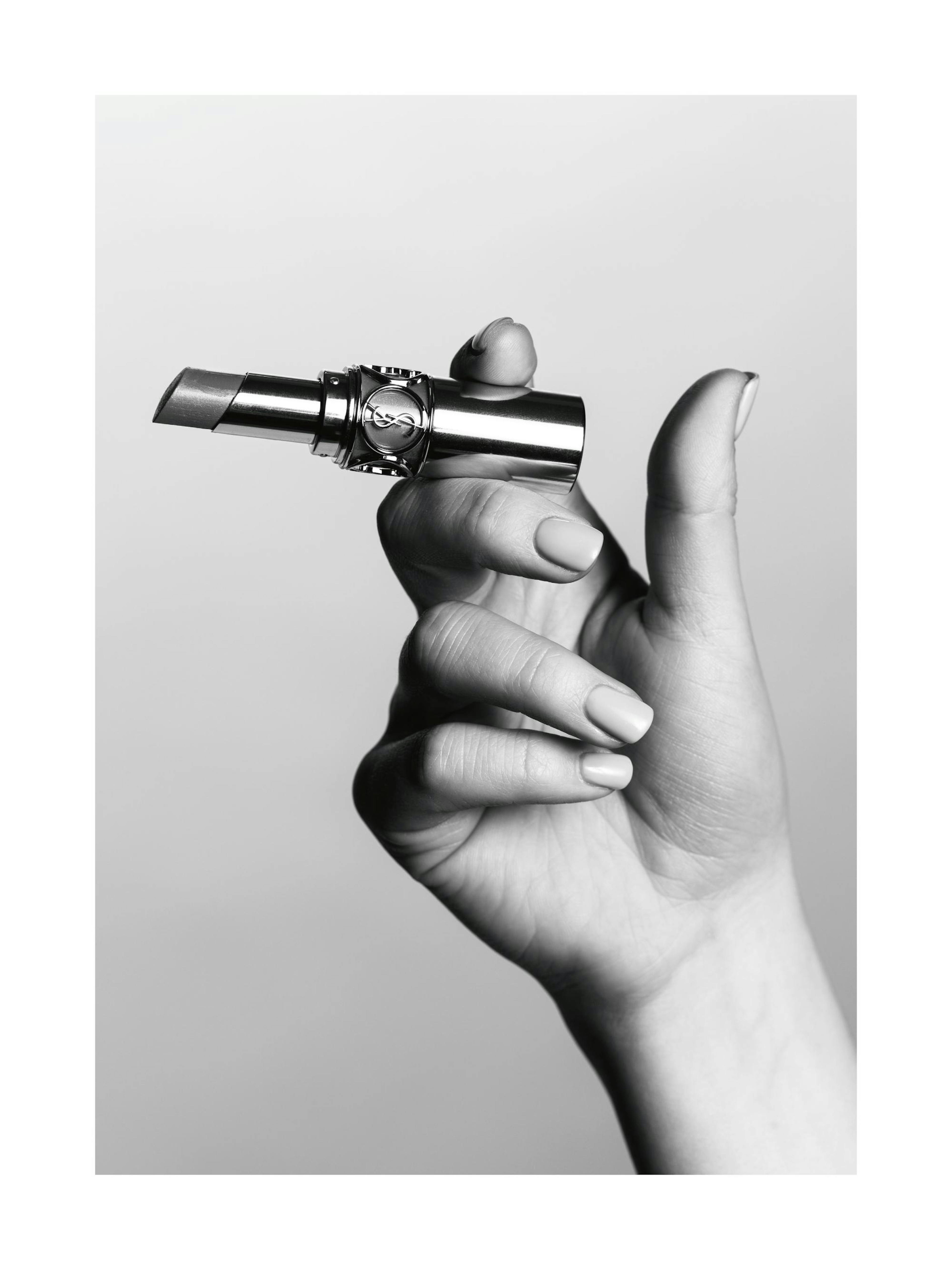 Svarthvitt-fotografi av en hånd som holder en YSL-leppestift som en sigarett, en stilig moteplakat.