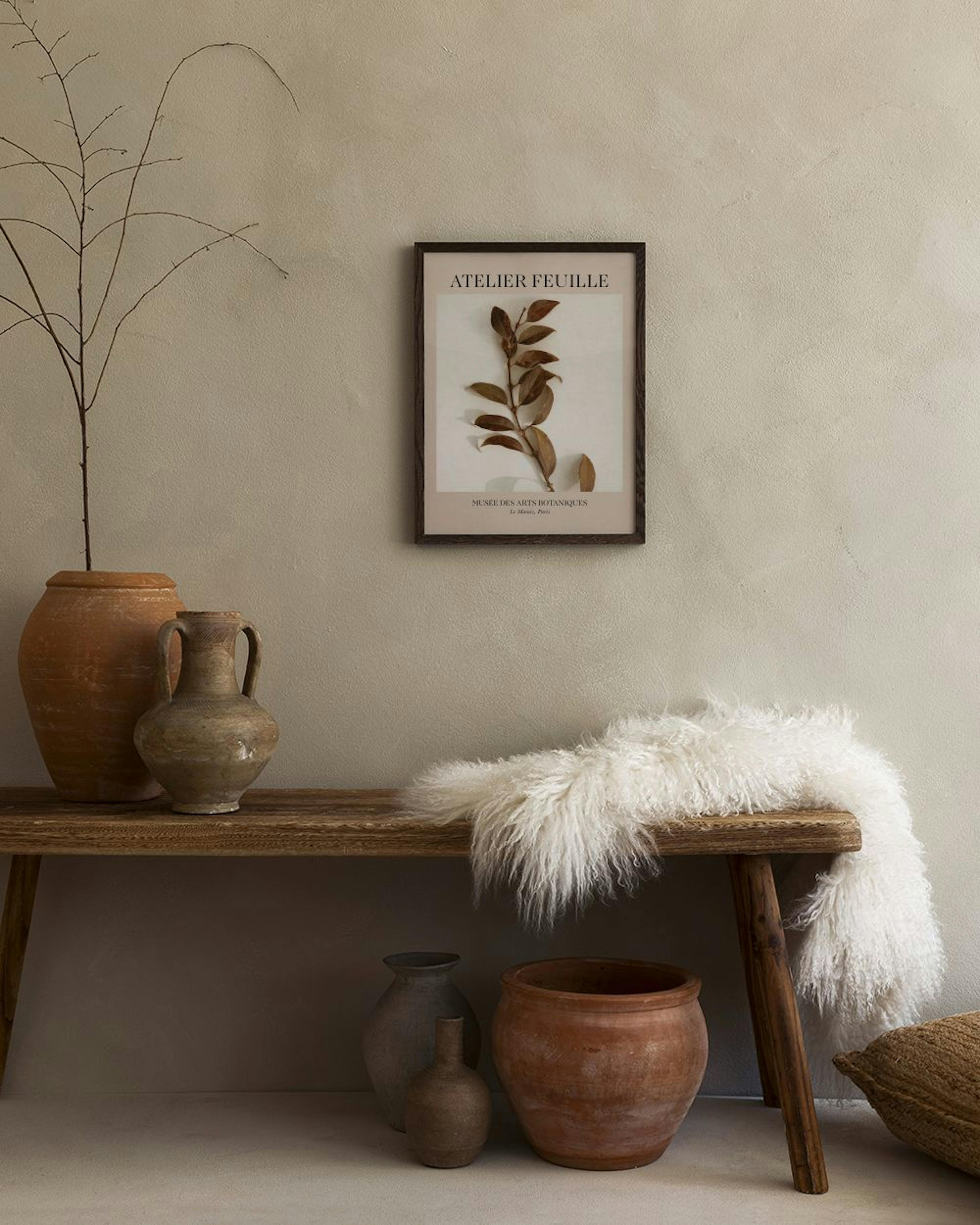 Affiche Atelier Feuille avec branche de feuilles séchées, suspendue au-dessus dun banc en bois rustique avec poterie et plaid bl