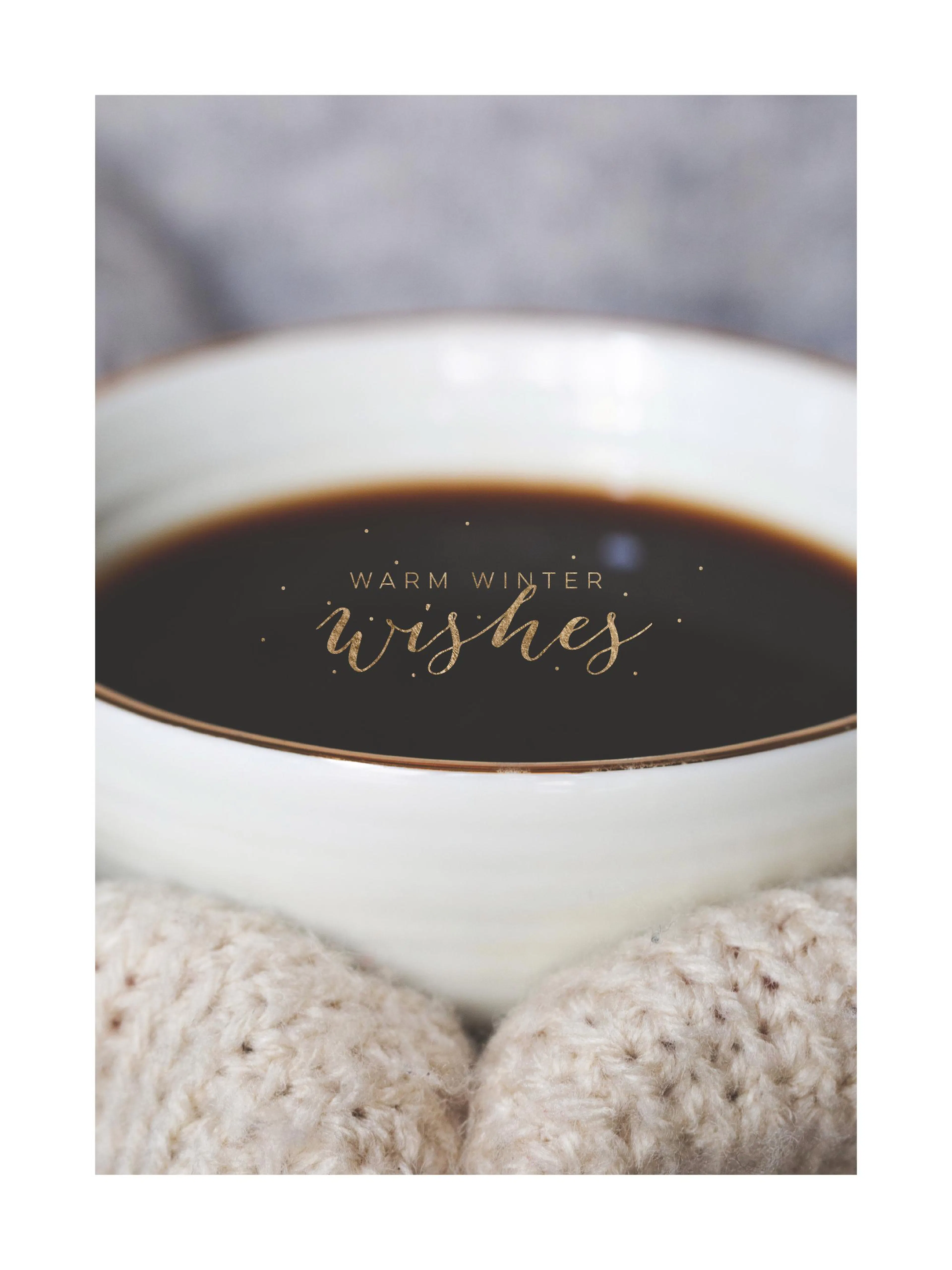 Primer plano de una taza de café caliente con el texto Warm Winter Wishes en oro y guantes de punto cremas.