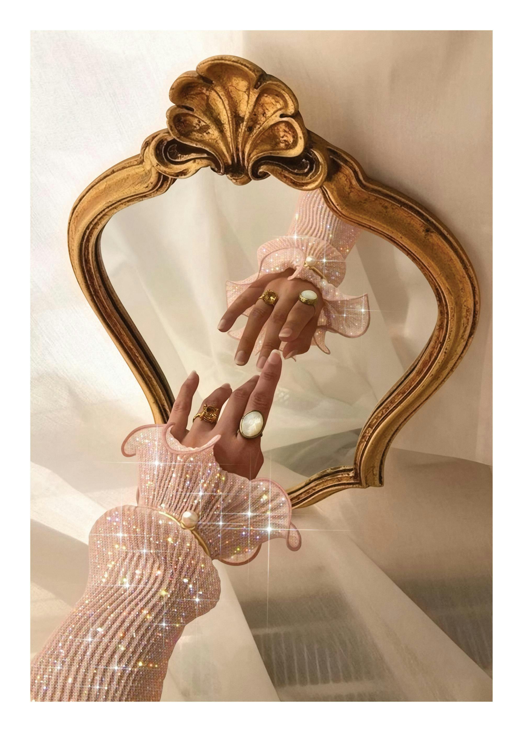 Photograph of an arm in a pink glittering sleeve reaching towards its reflection in an ornate gold mirror, creating a dreamy aes