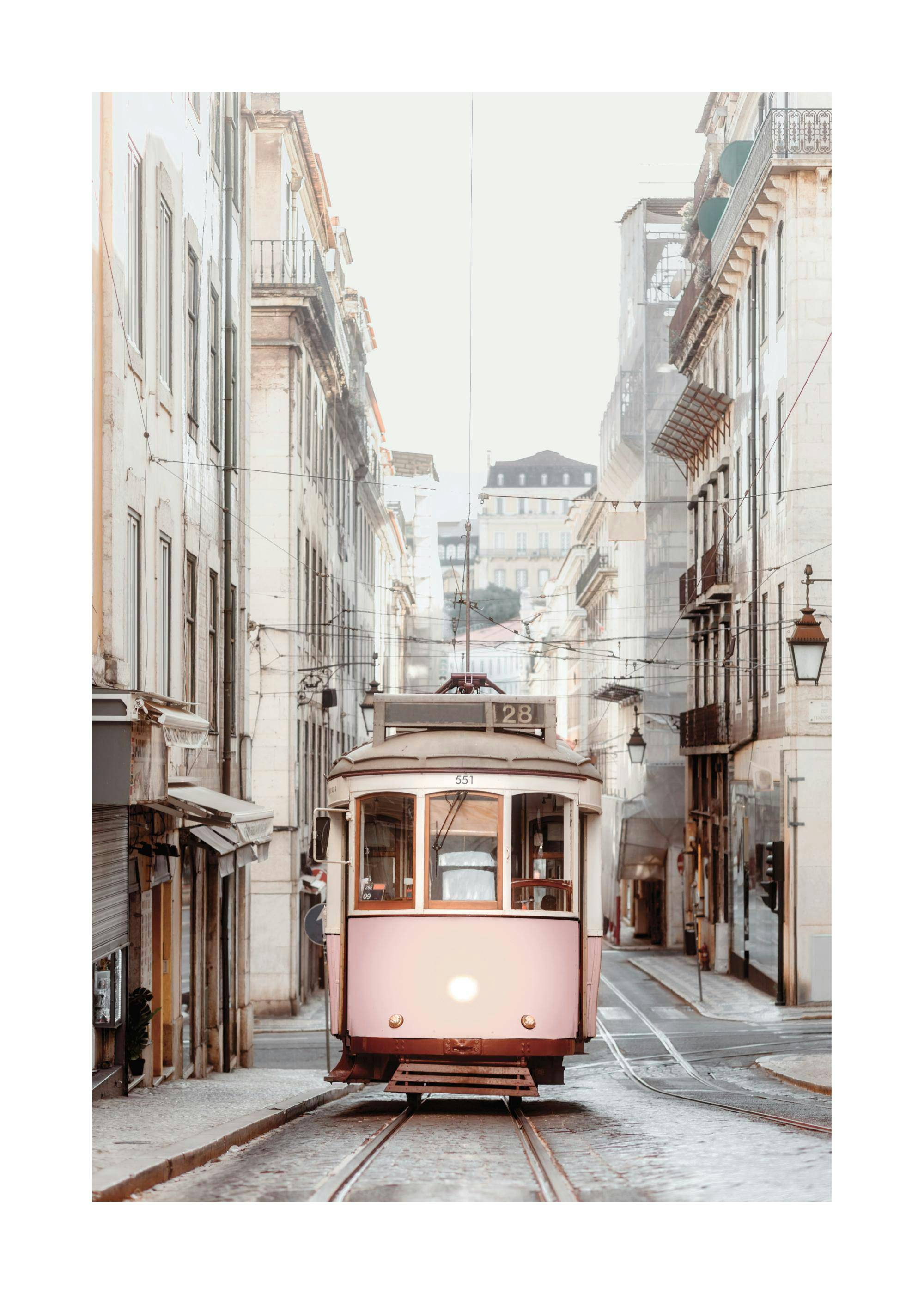 Póster de fotografía vintage de un tranvía rosa antiguo en una calle adoquinada con edificios tradicionales en un día brumoso.