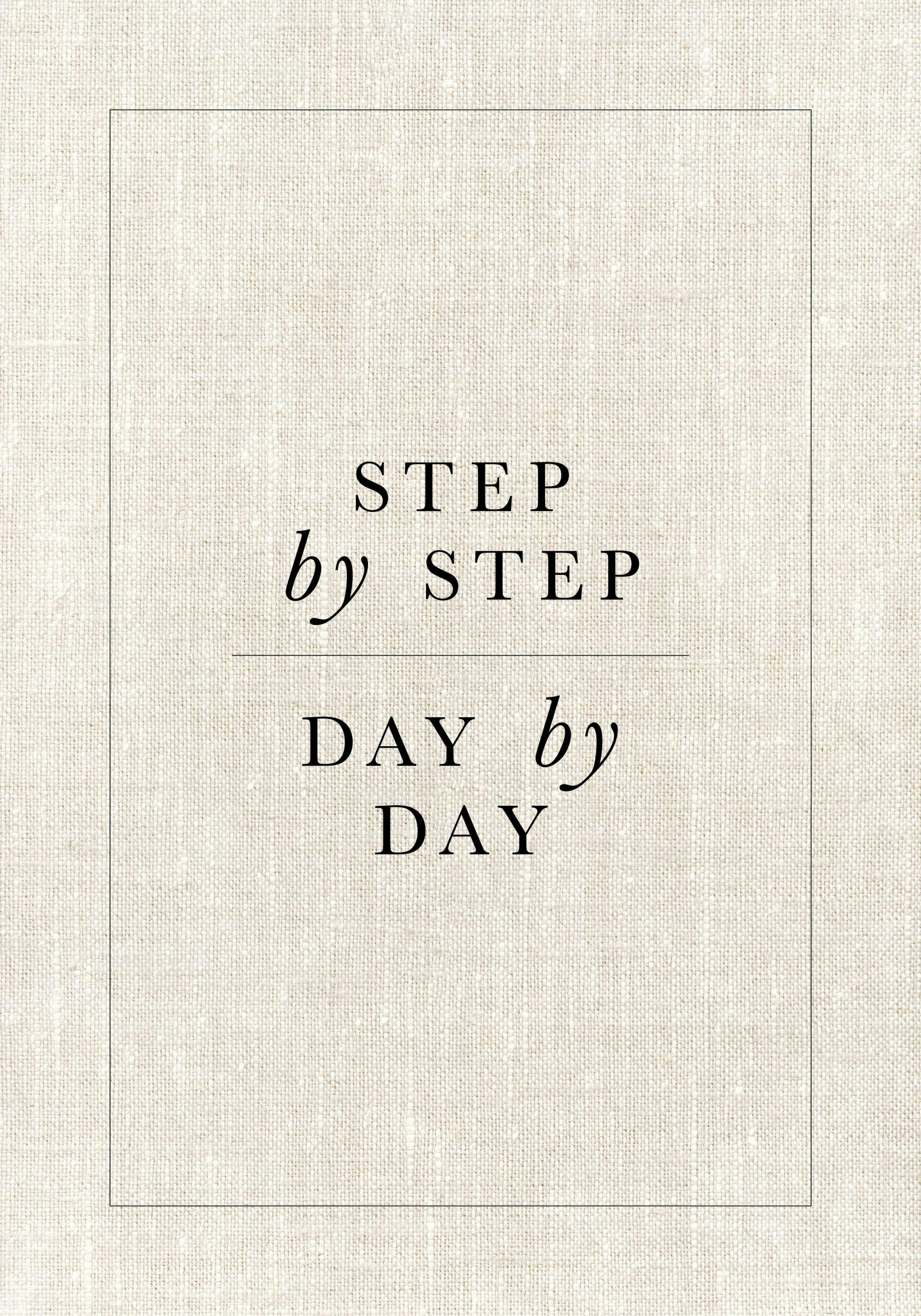 En poster med texten Step by step, day by day i svart på en beige bakgrund, med en tunn ram.