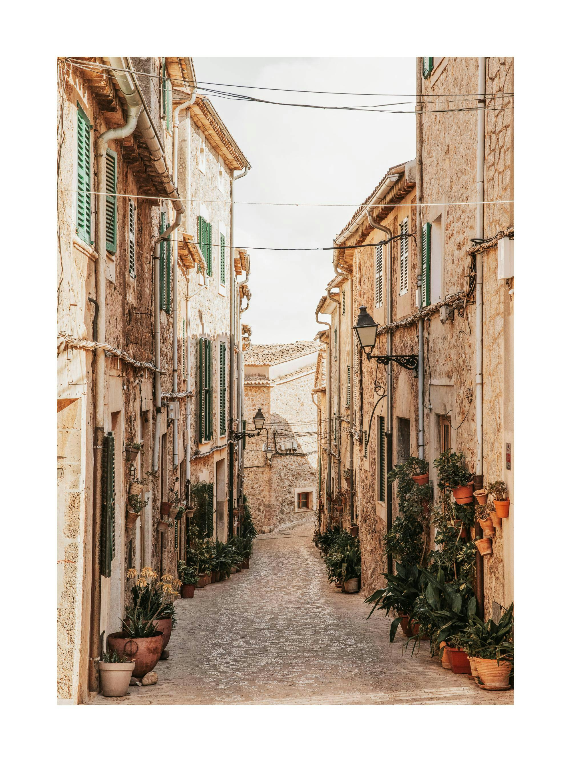 Valldemossa gydefotografi med brosten, stentøjsbygninger, grønne skodder og frodige potteplanter, Mallorca.