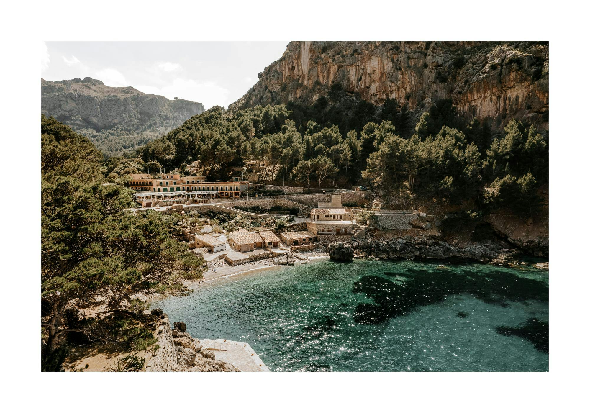 Fotografi av Sa Calobra-stranden på Mallorca med turkost vatten och gröna berg. Perfekt för strand- och naturälskare.