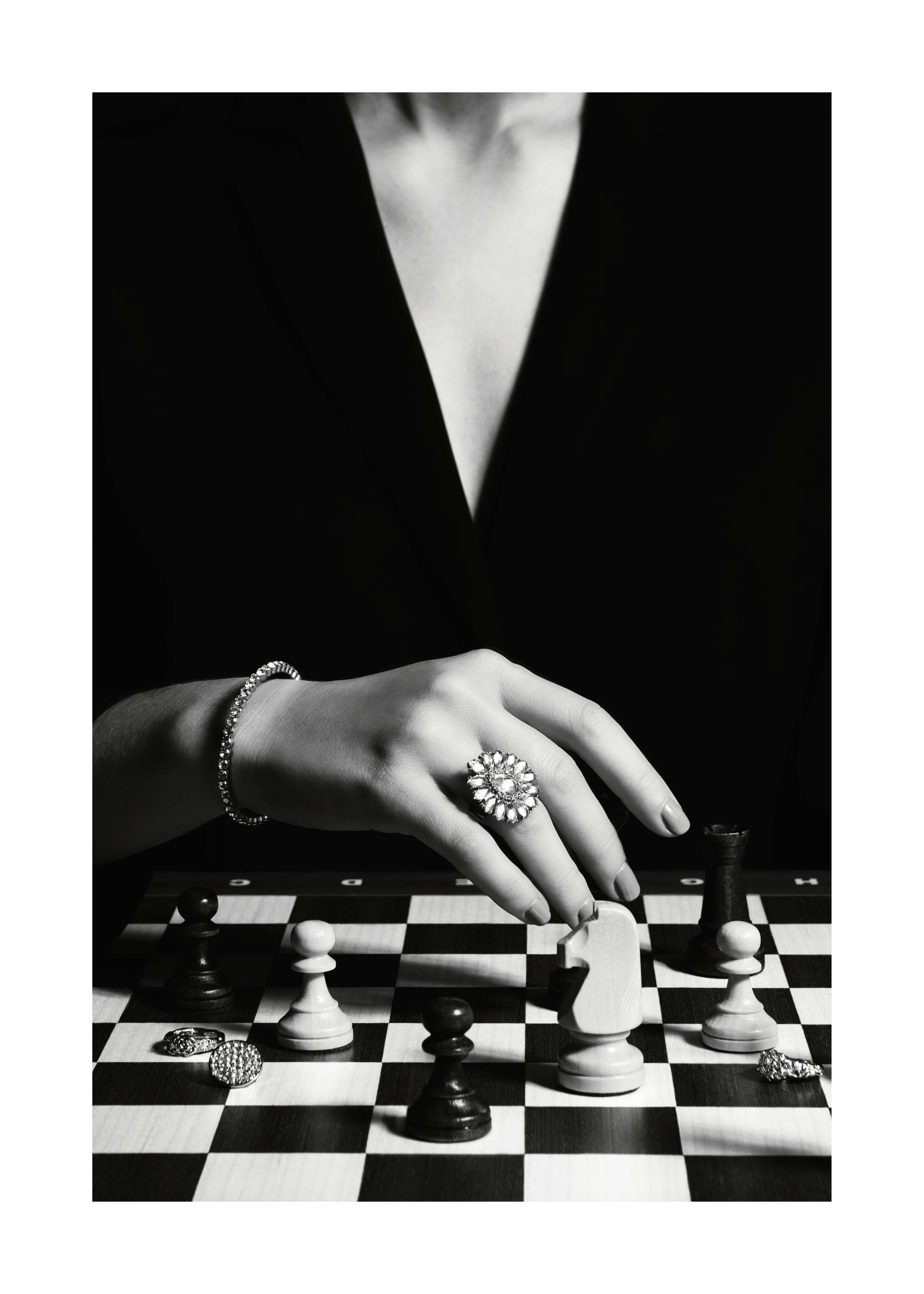 Poster in bianco e nero: donna con anello e bracciale che gioca a scacchi, stile classico e senza tempo.