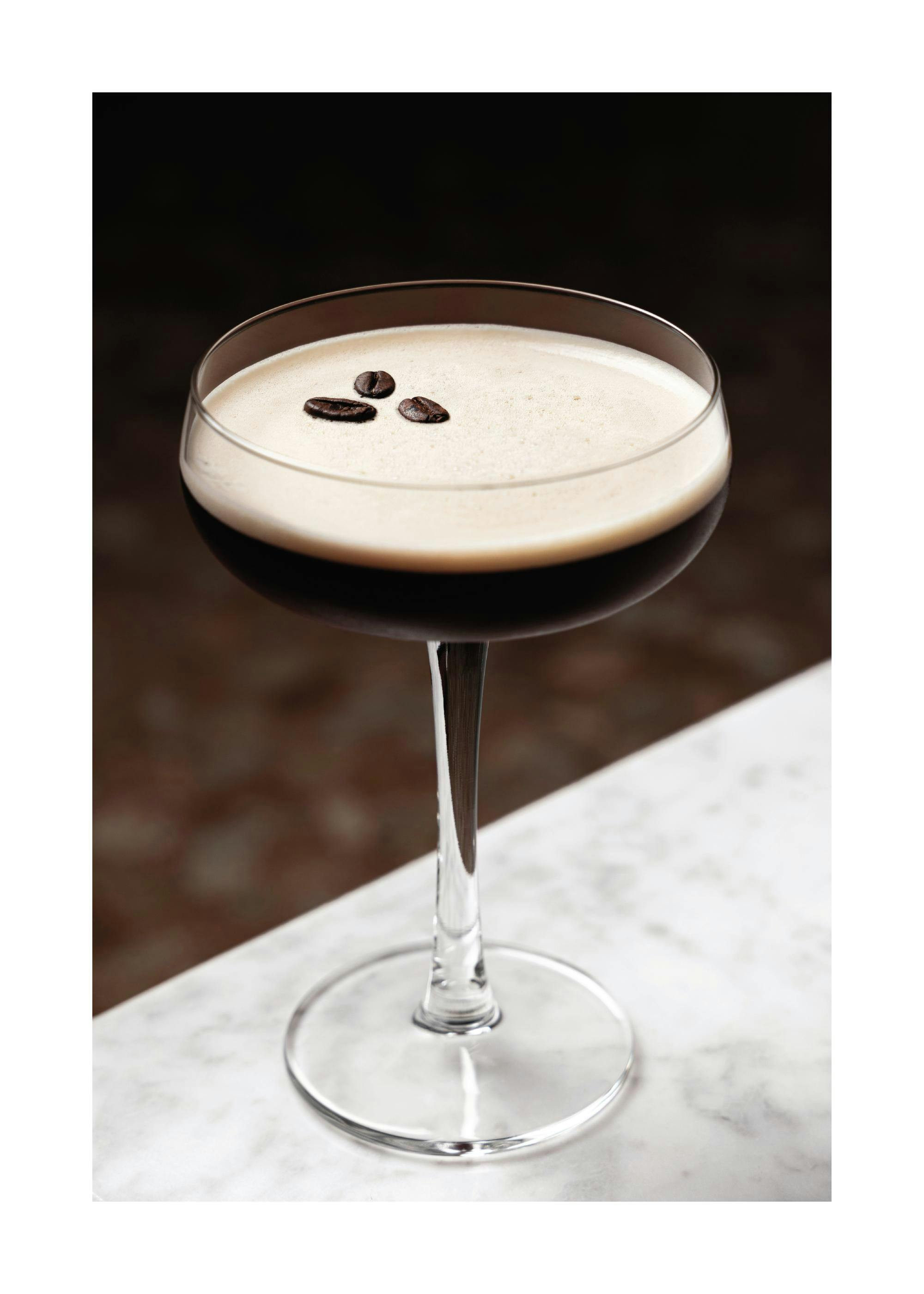 Affiche dune boisson au café avec mousse et trois grains de café, posée sur une table en marbre blanc