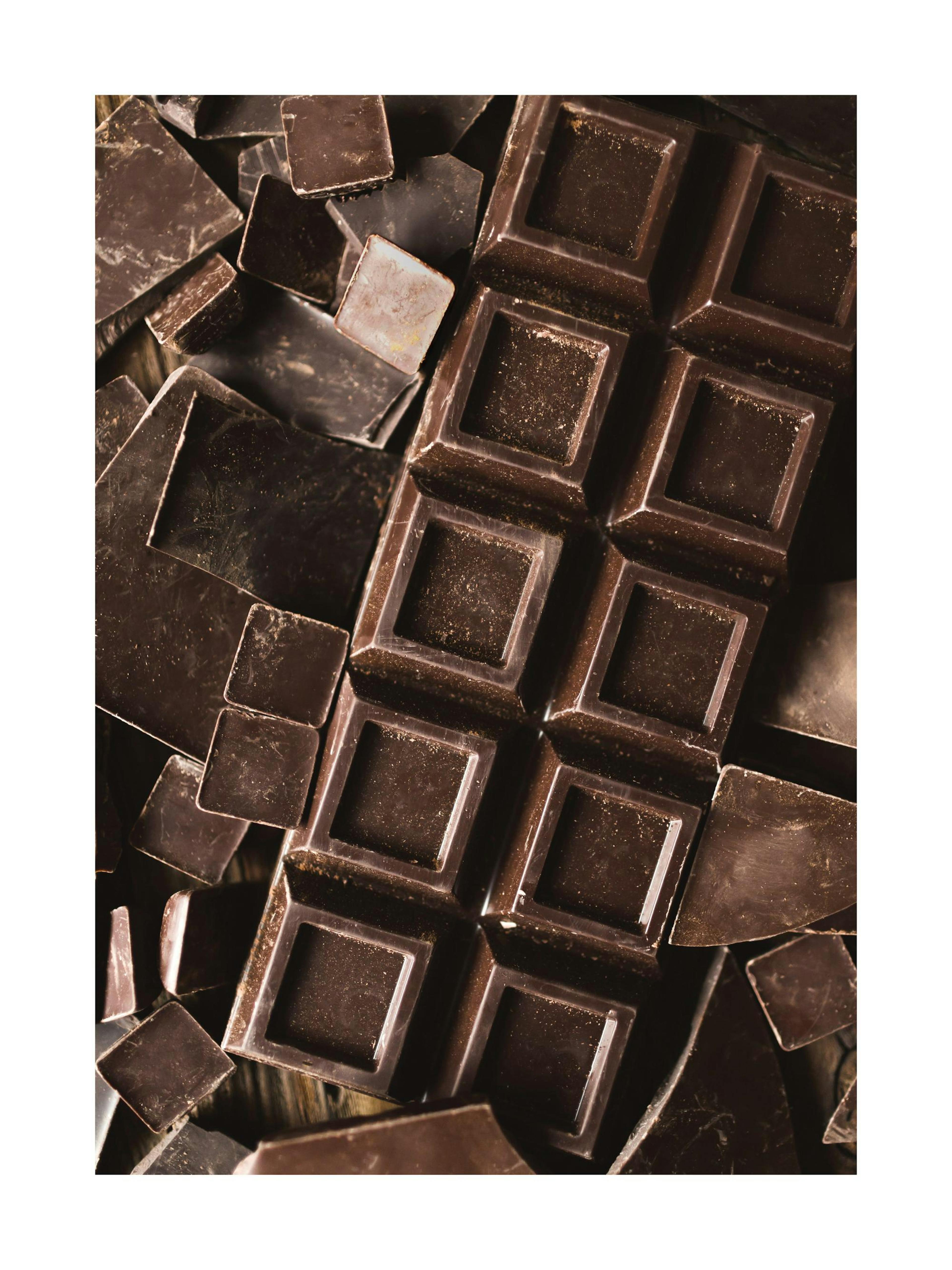 Barra de chocolate negro y trozos. Fotografía de alimentos, repostería y postres.