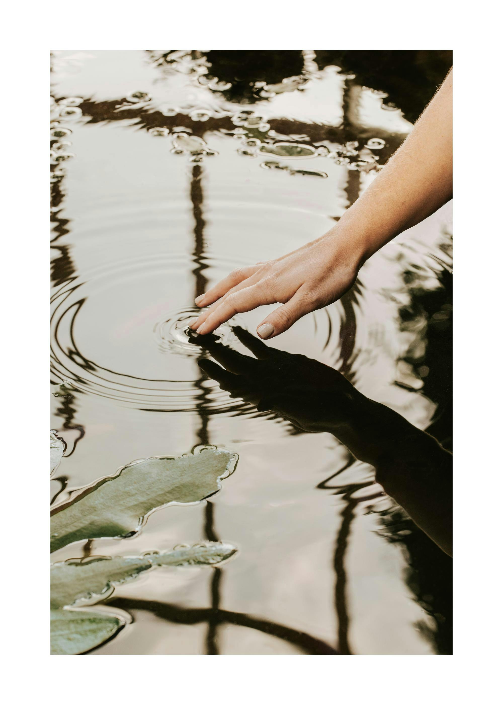 Hand creating ripples in water, a calming photographic print or poster for home decor.