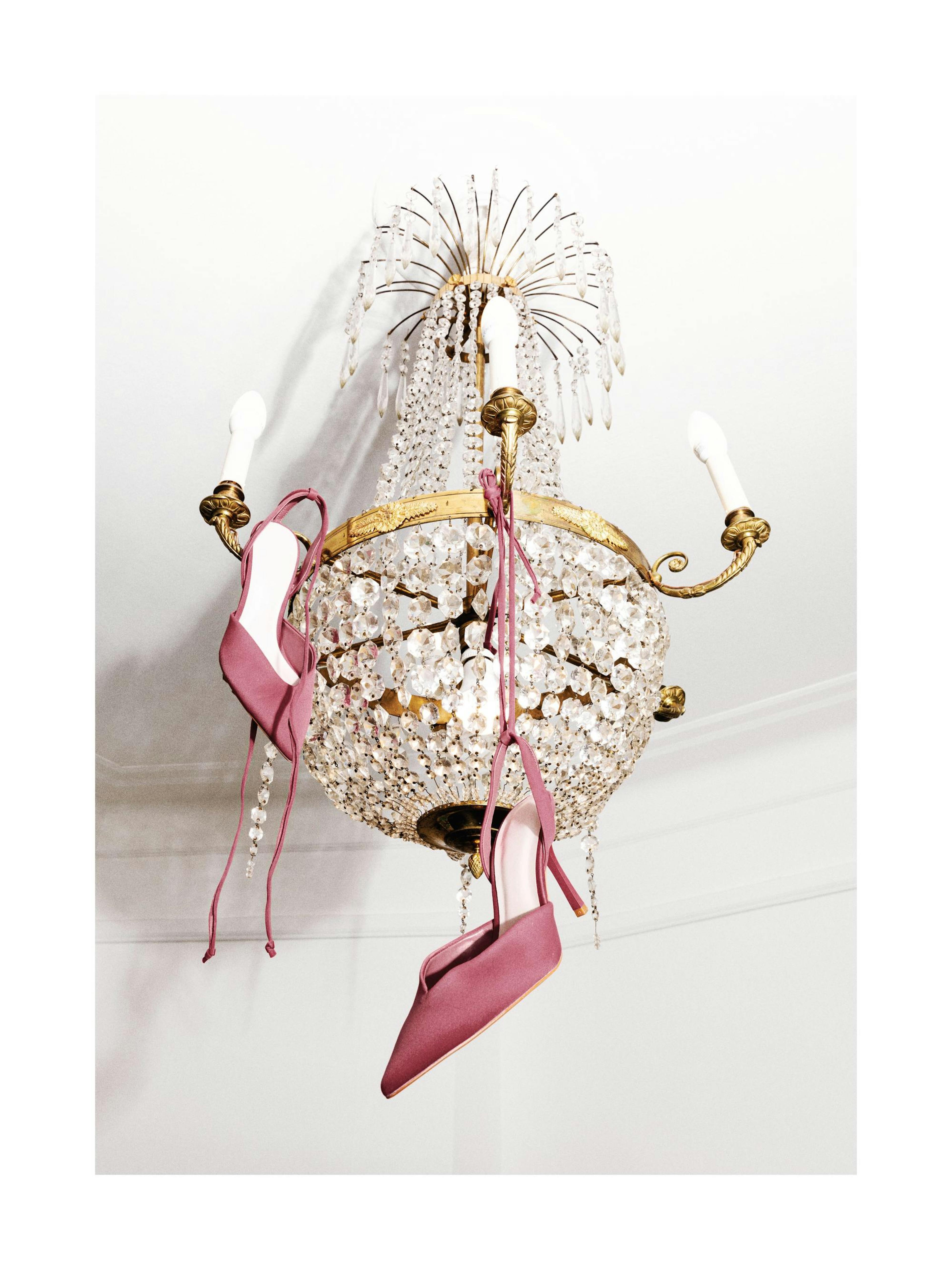 Póster: tacones rosa colgando de una lámpara de araña de cristal, fotografía de moda divertida
