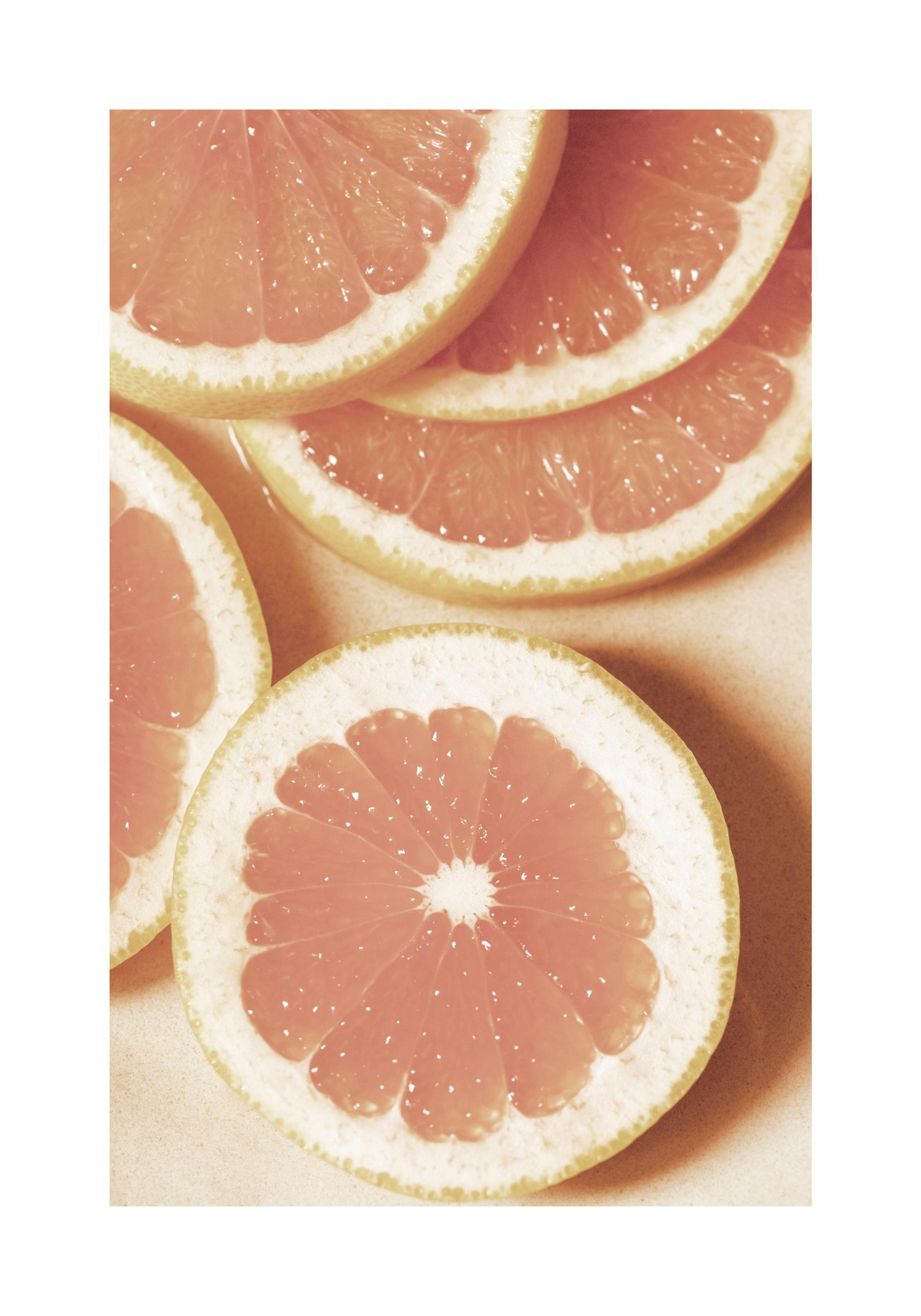 Fotografie von aufgeschnittenen Grapefruitscheiben in heiterem Orange, ideal für Küchen-Wandkunst.