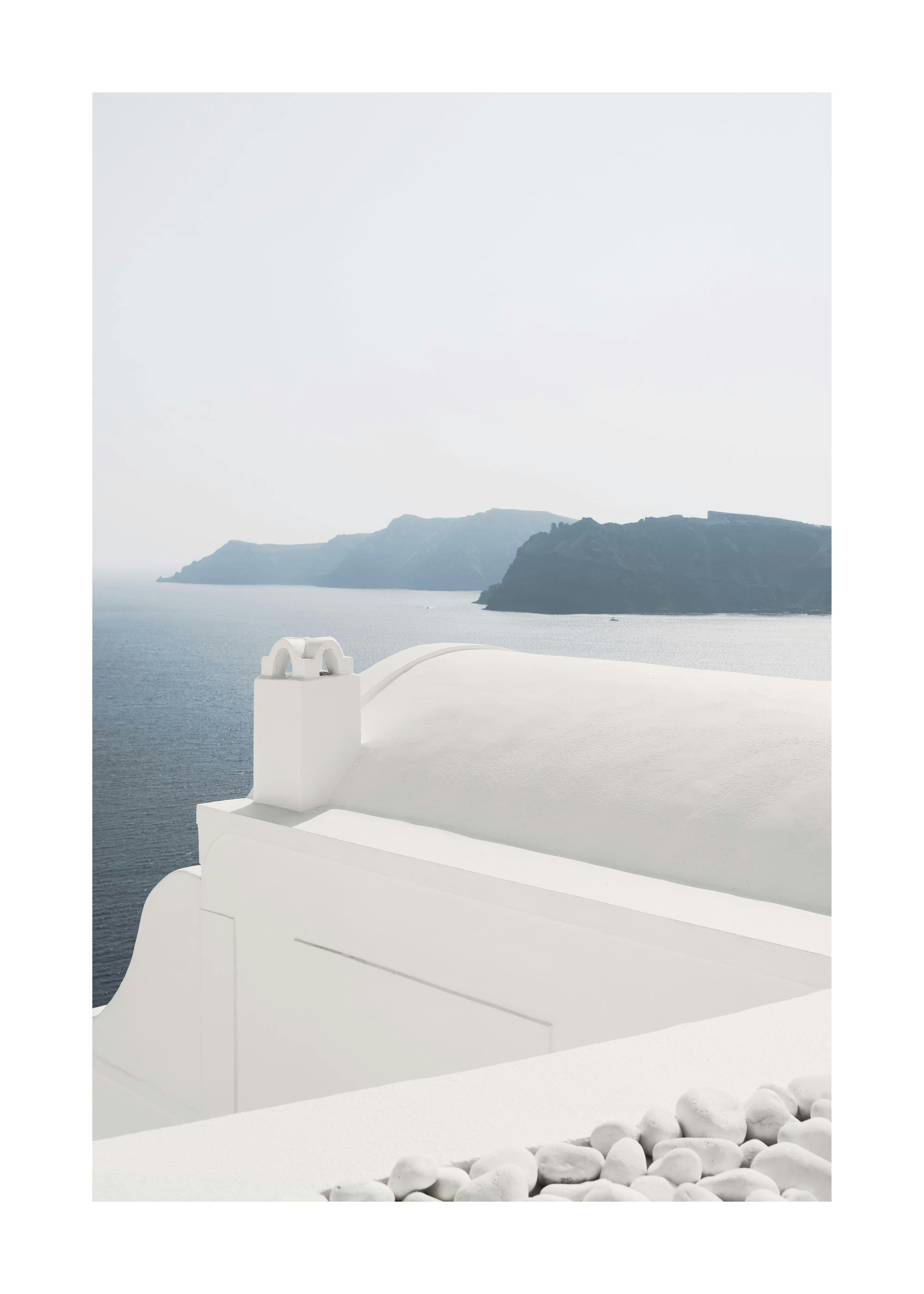 Ocean view from a whitewashed Greek house rooftop with white pebbles