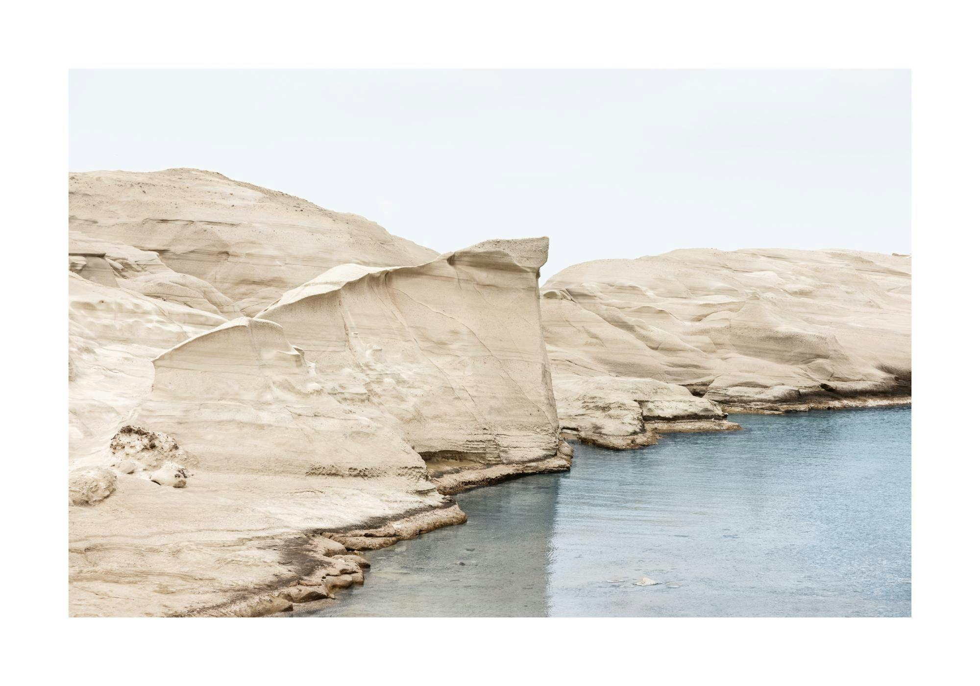 Milos månlandskap poster med vita eroderade klippor och lugnt, klart blått hav under en ljus himmel.