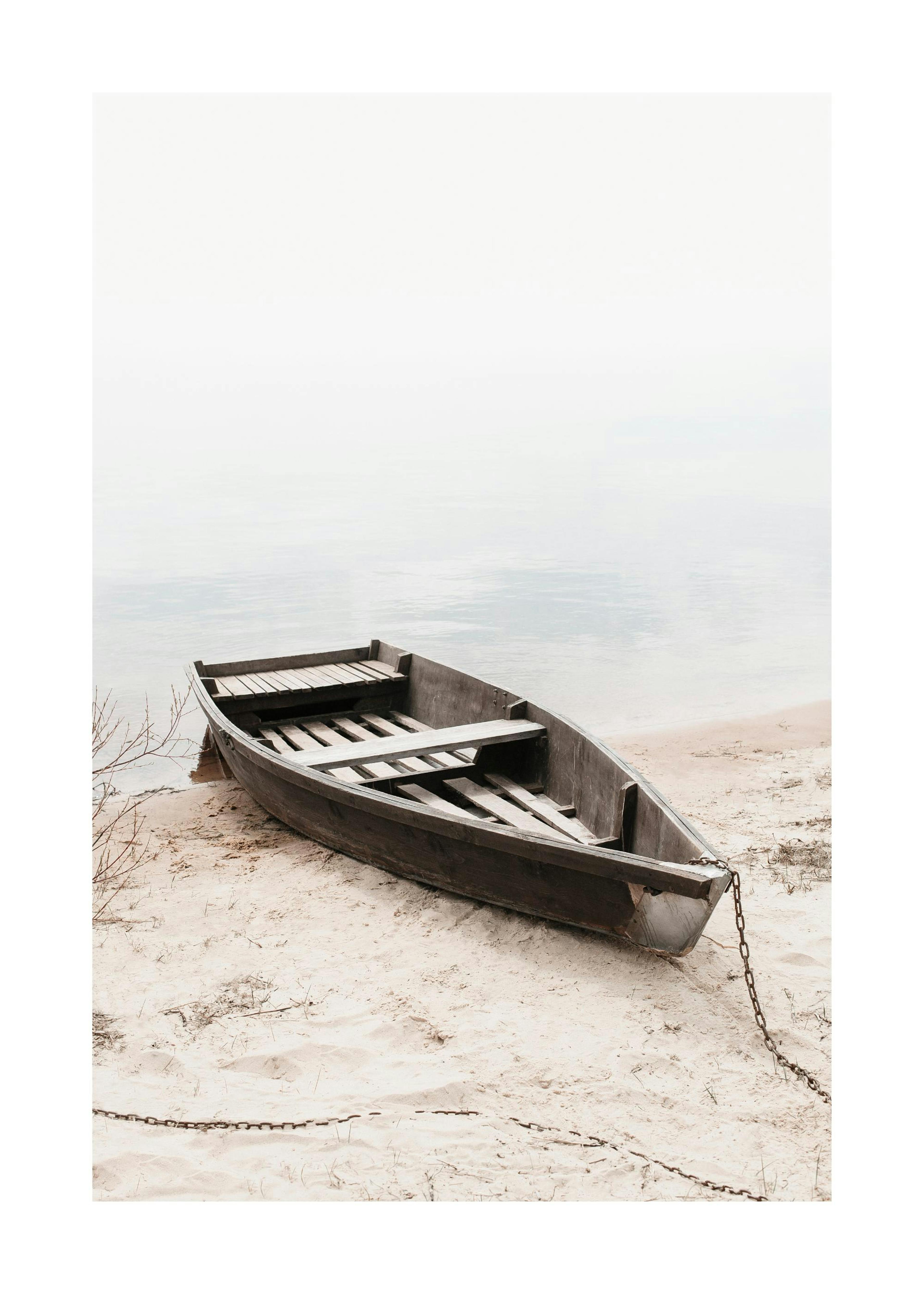 Stranded wooden boat on a sandy shore with a metal chain, calm water in the background, tranquil marine photography.